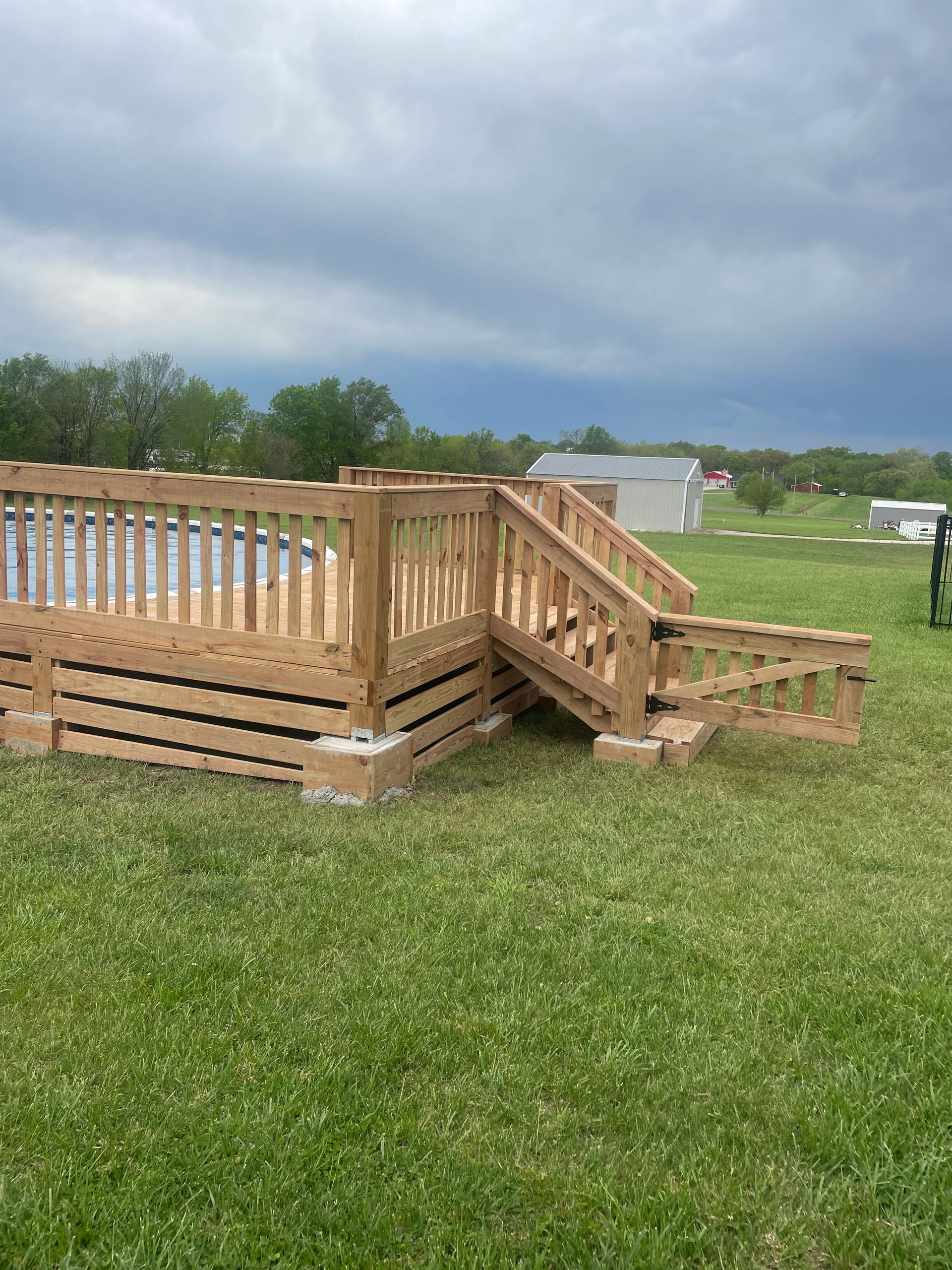 A wooden deck with stairs is sitting in the middle of a grassy field.