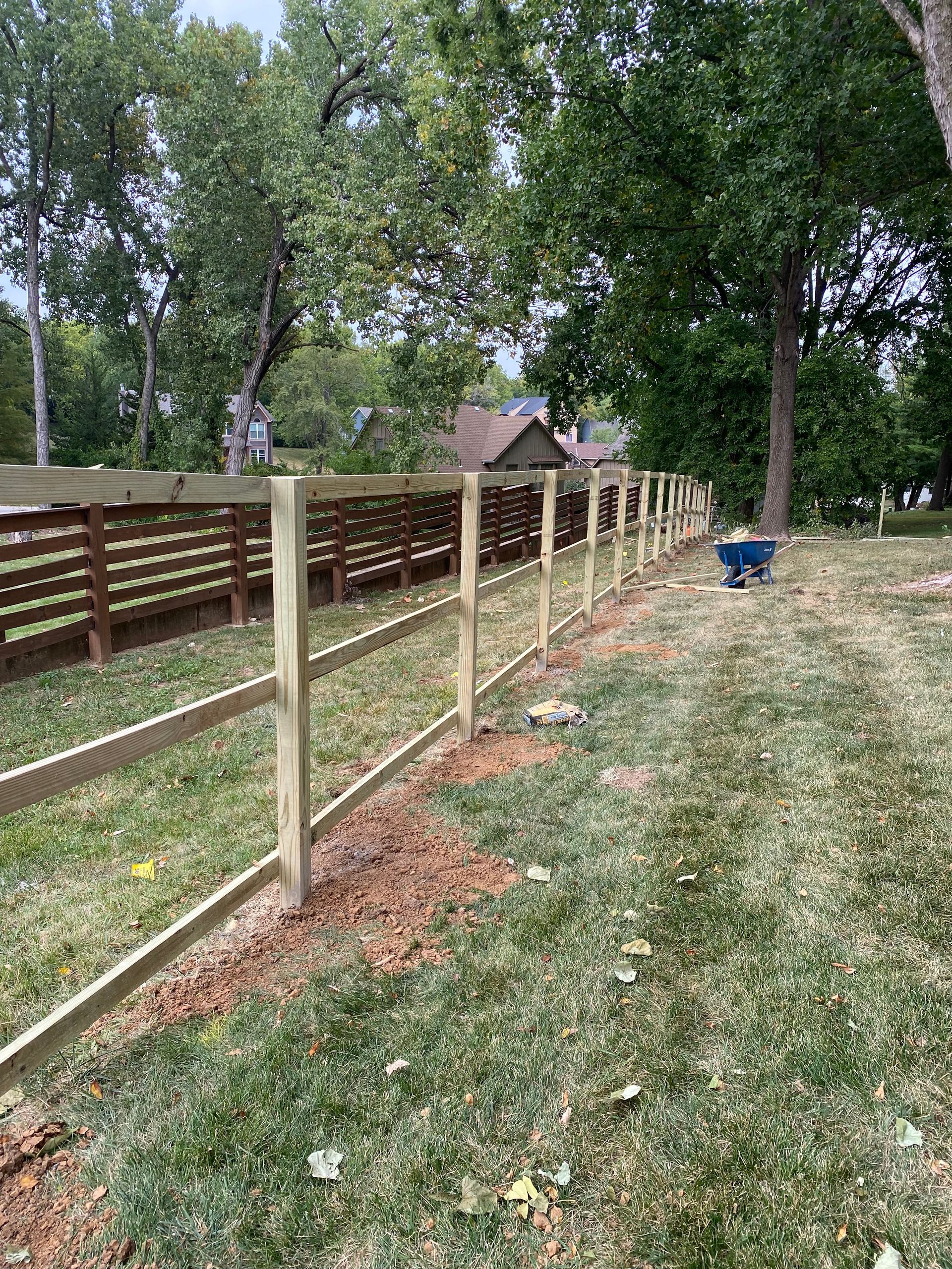 A wooden fence is being built in the middle of a lush green field.