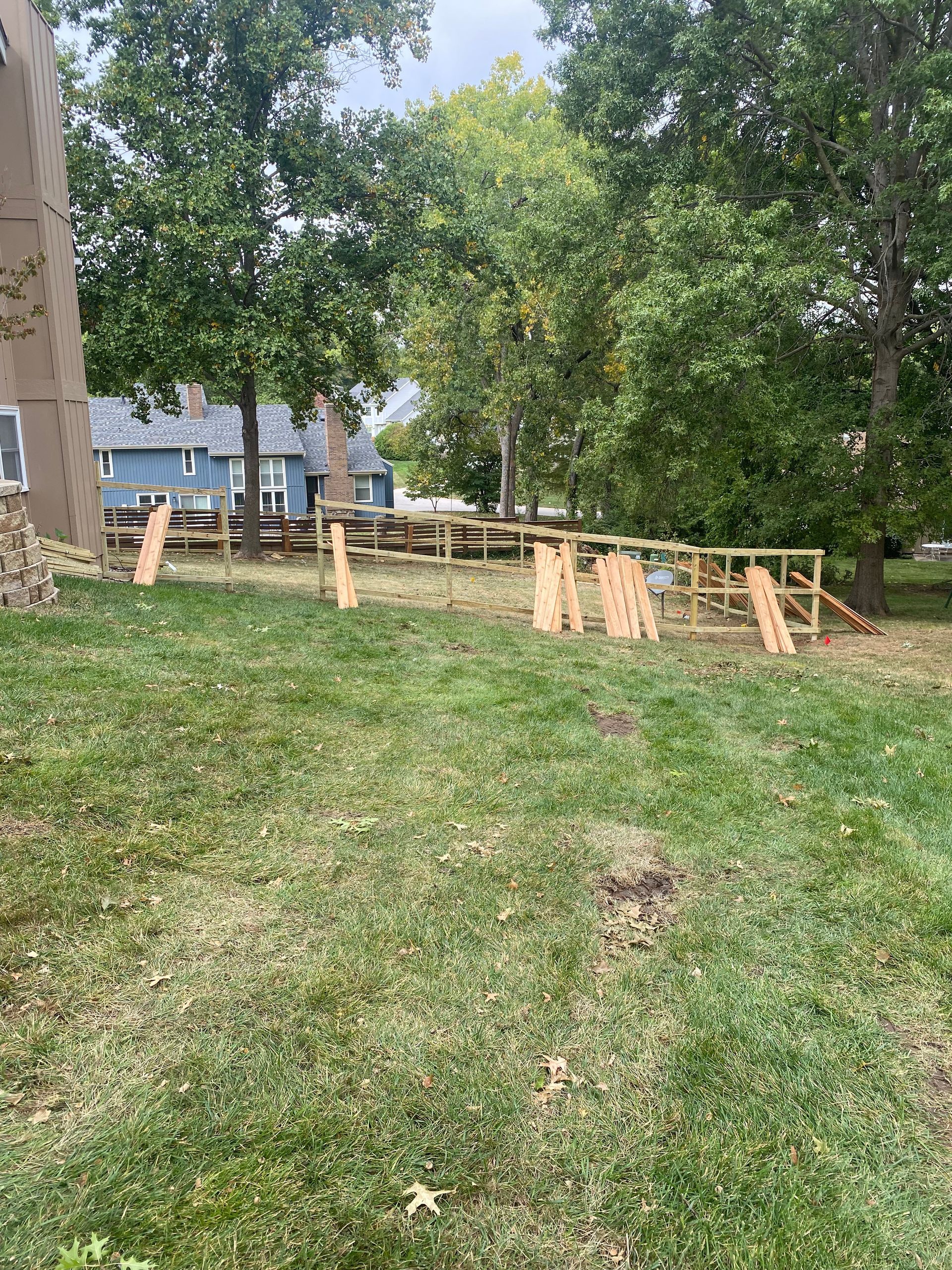 A wooden fence is sitting in the middle of a lush green field.
