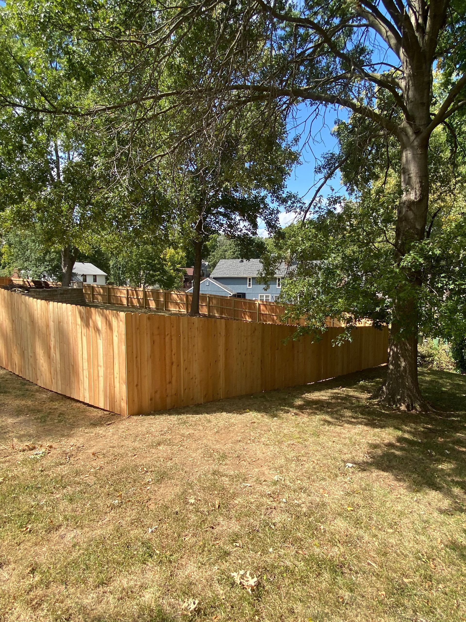 A wooden fence is surrounded by trees in a yard.