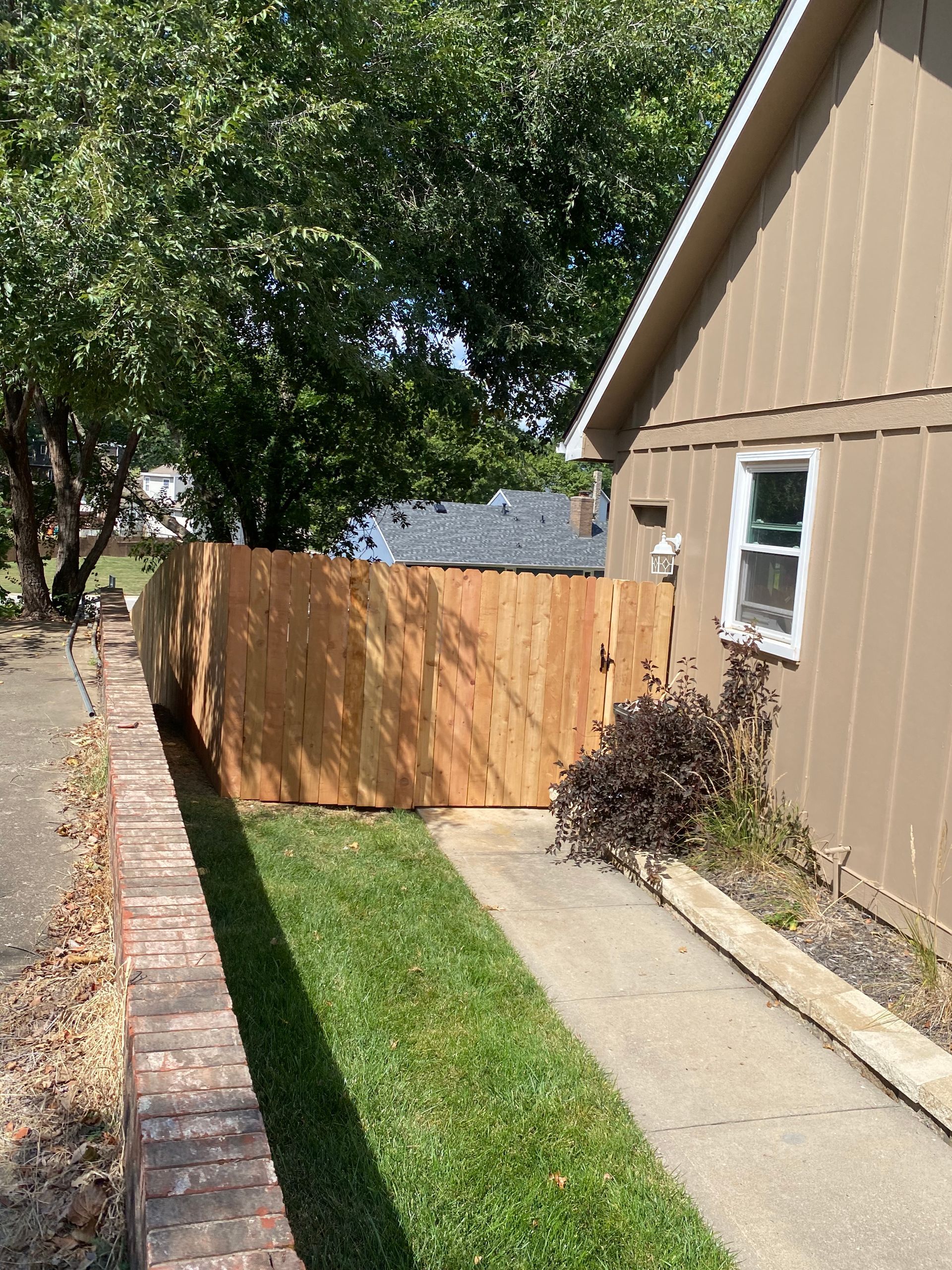 A wooden fence along a sidewalk next to a house.