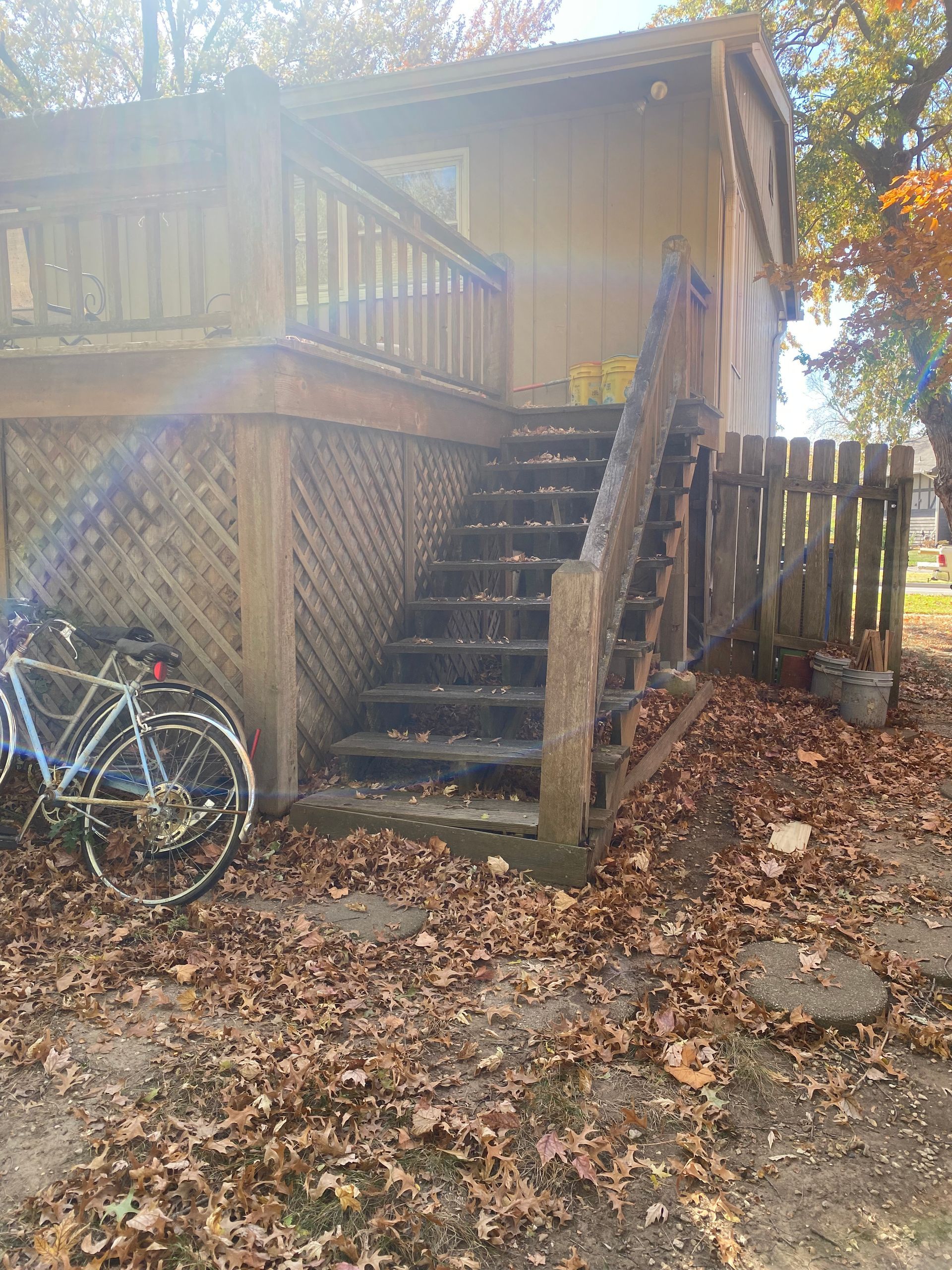 A bicycle is parked in front of a house with stairs leading up to it.