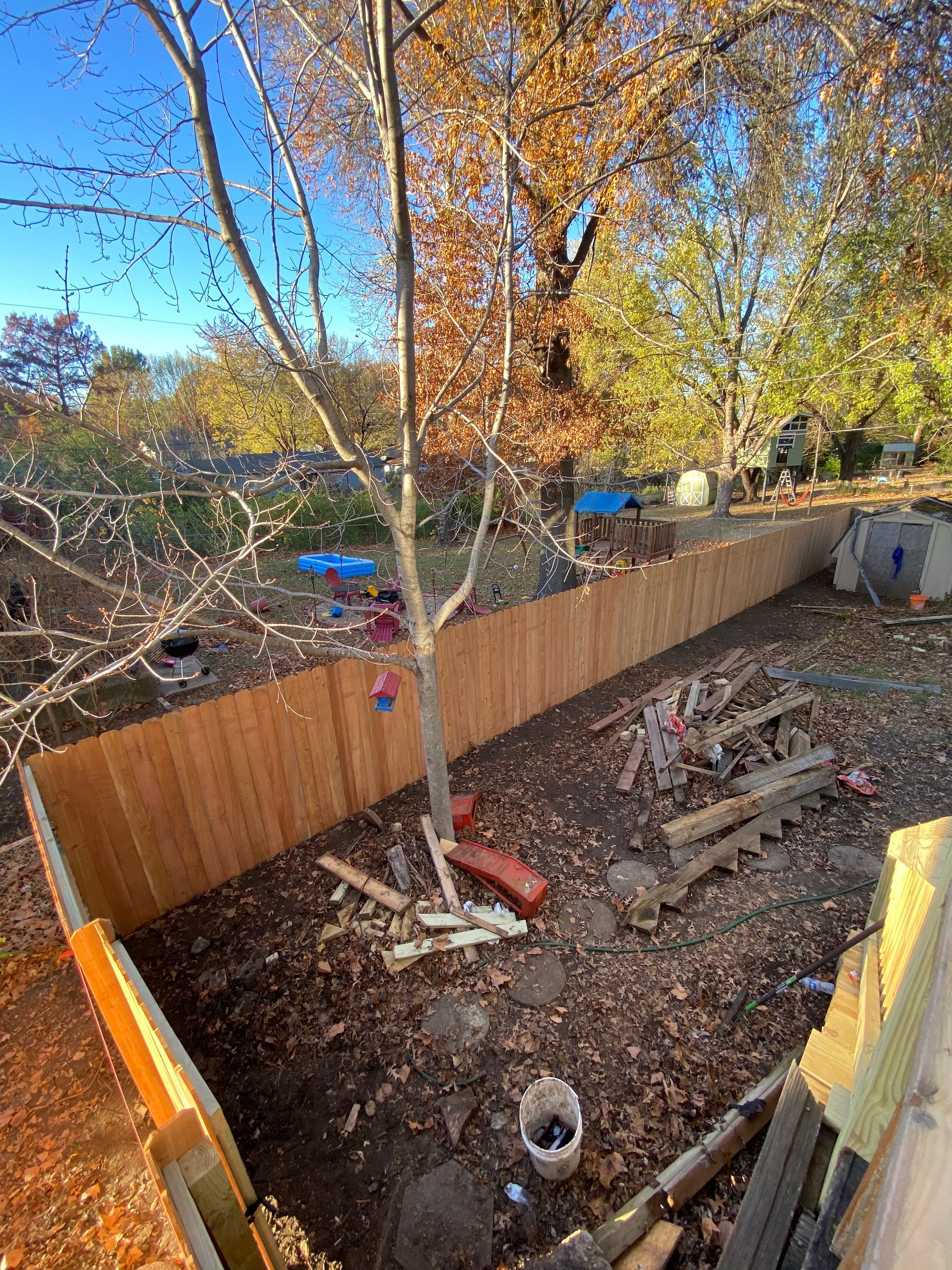 A wooden fence is being built in a backyard.