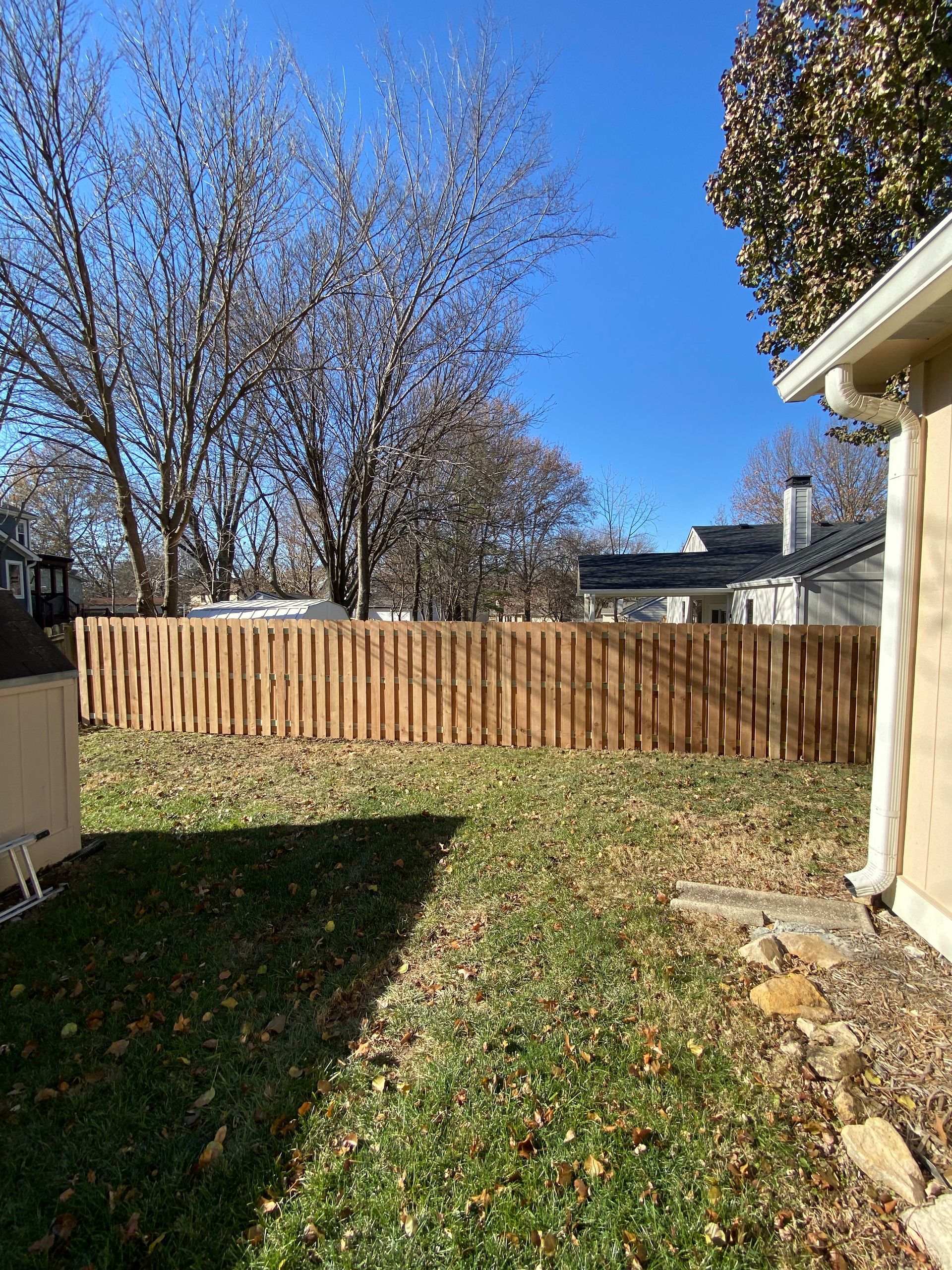 There is a wooden fence in the backyard of a house.