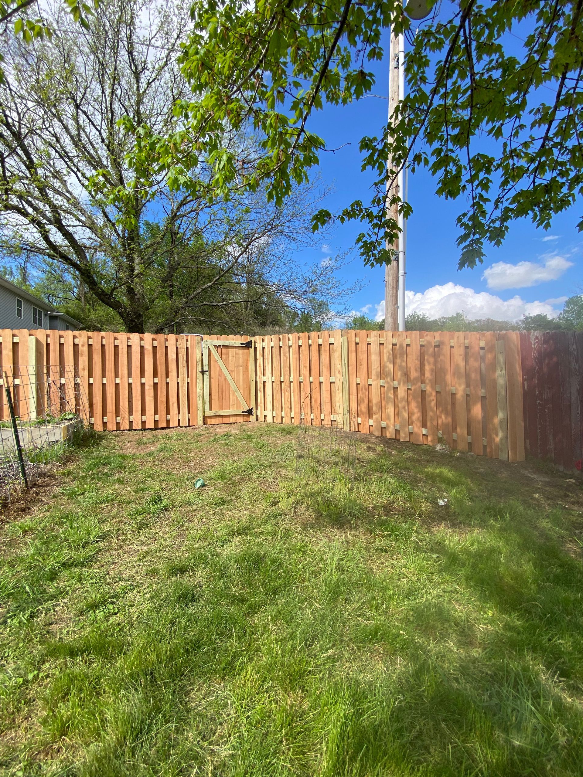 A wooden fence is sitting in the middle of a lush green yard.