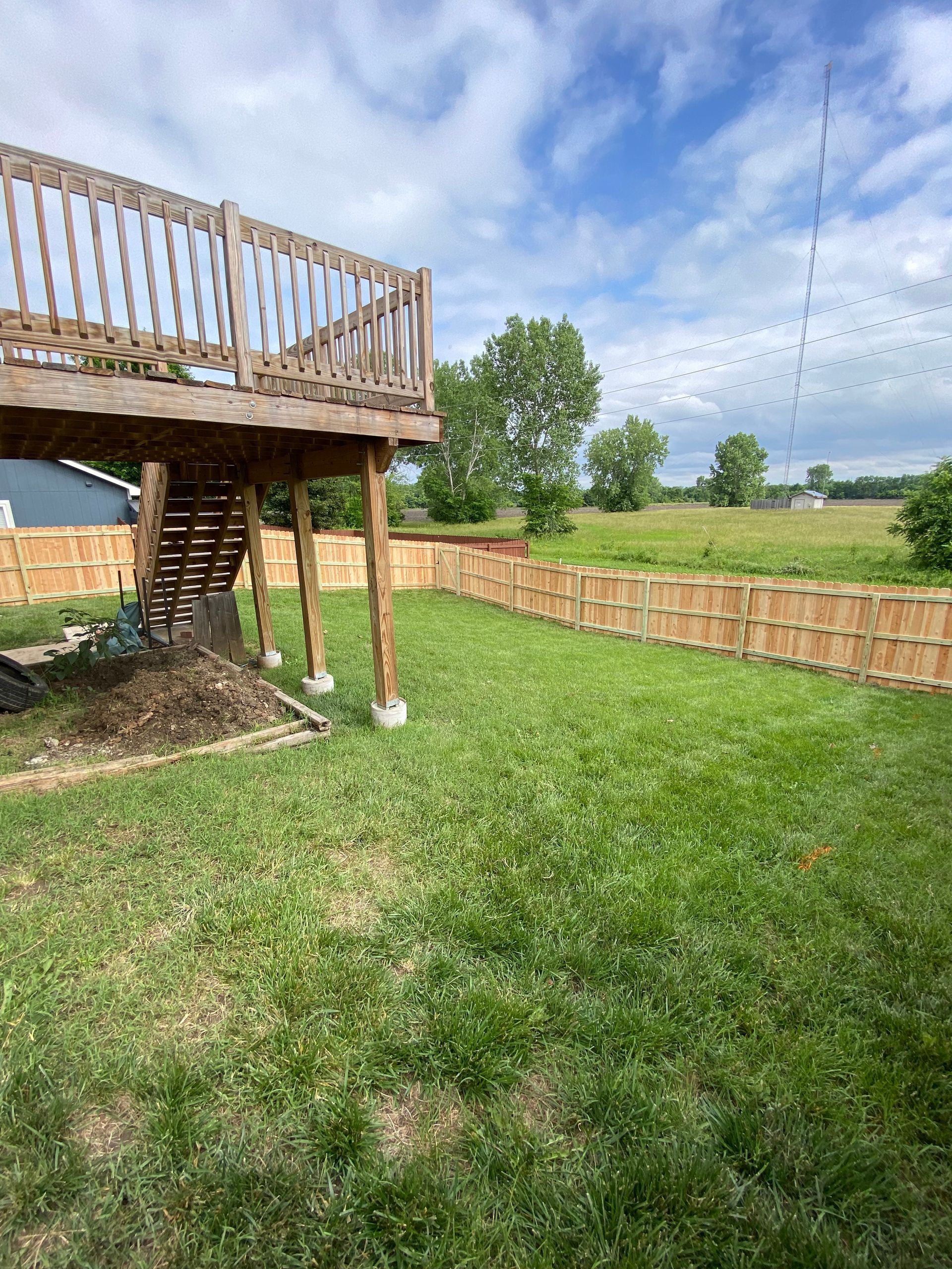 A backyard with a wooden deck and a wooden fence.