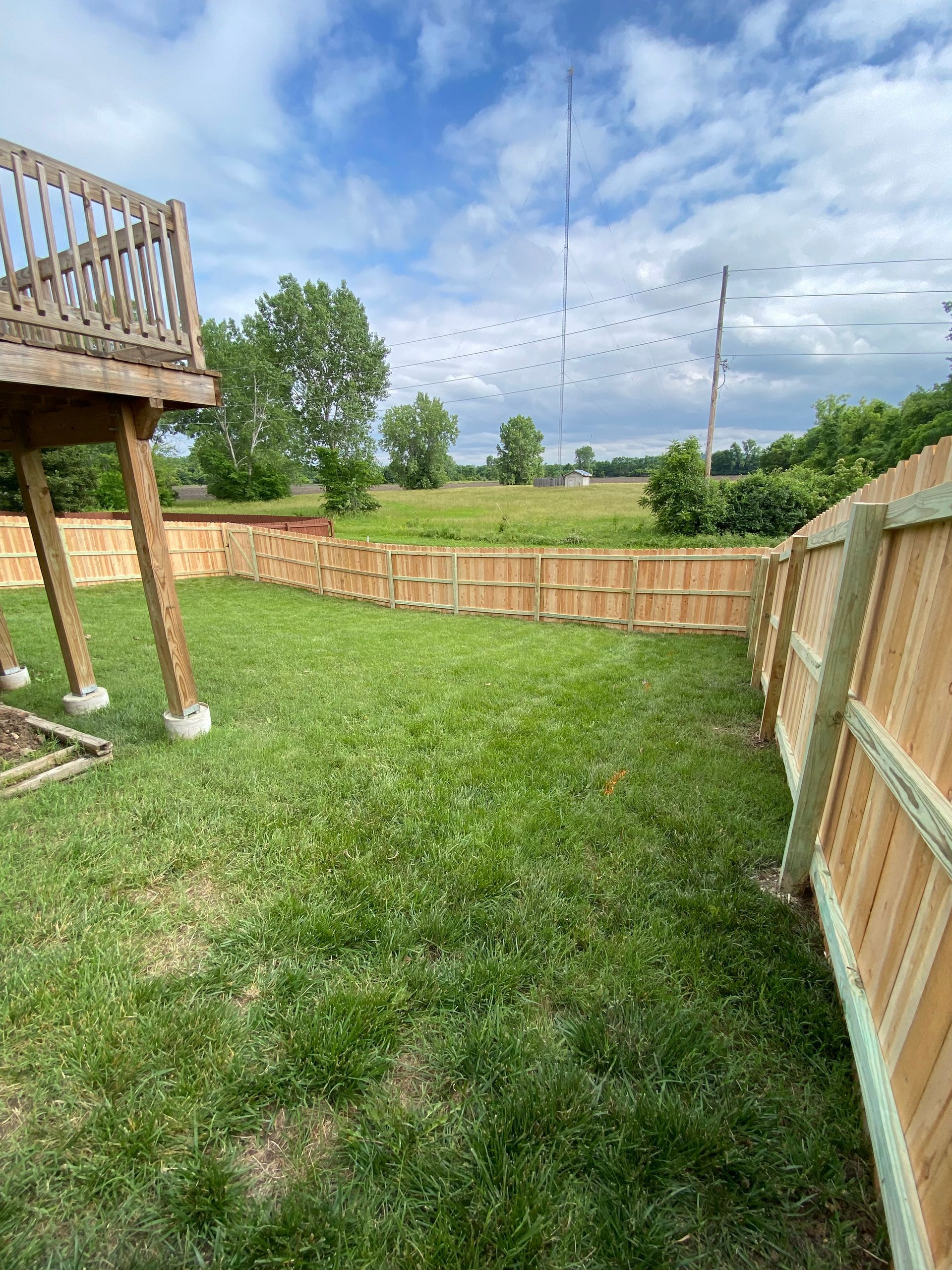 A backyard with a wooden fence and a deck.