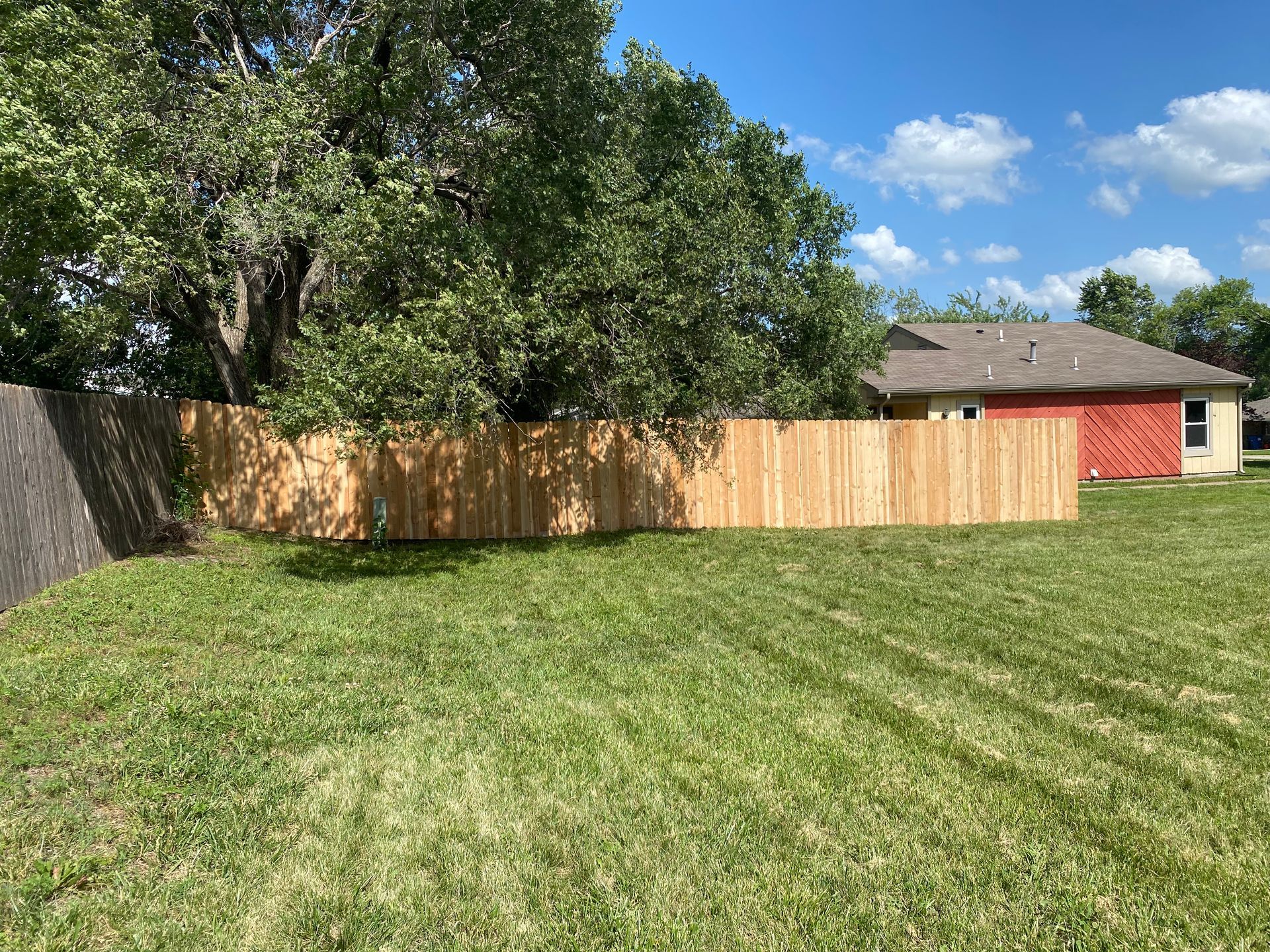 There is a wooden fence in the backyard of a house.