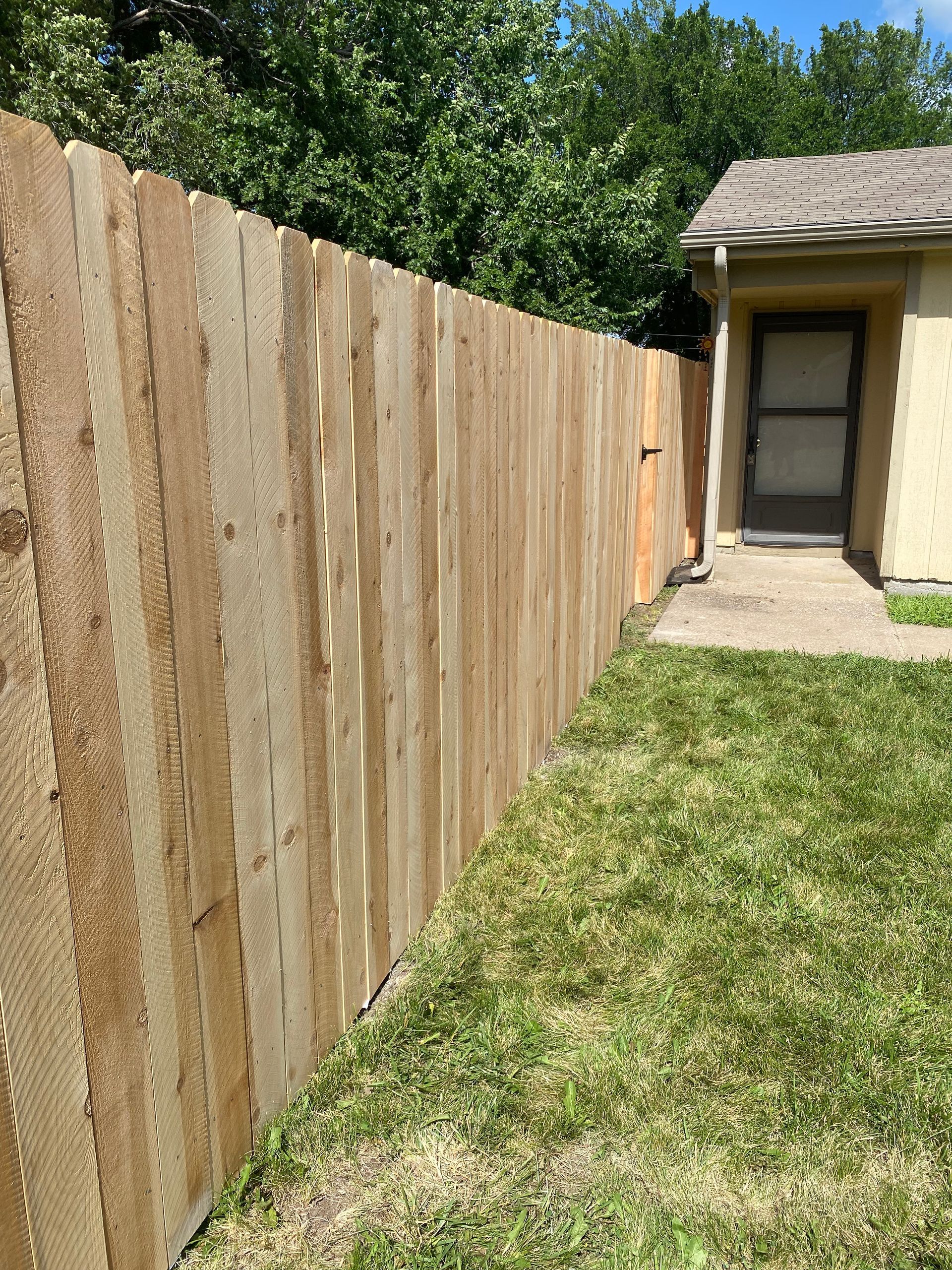A wooden fence is in the backyard of a house.