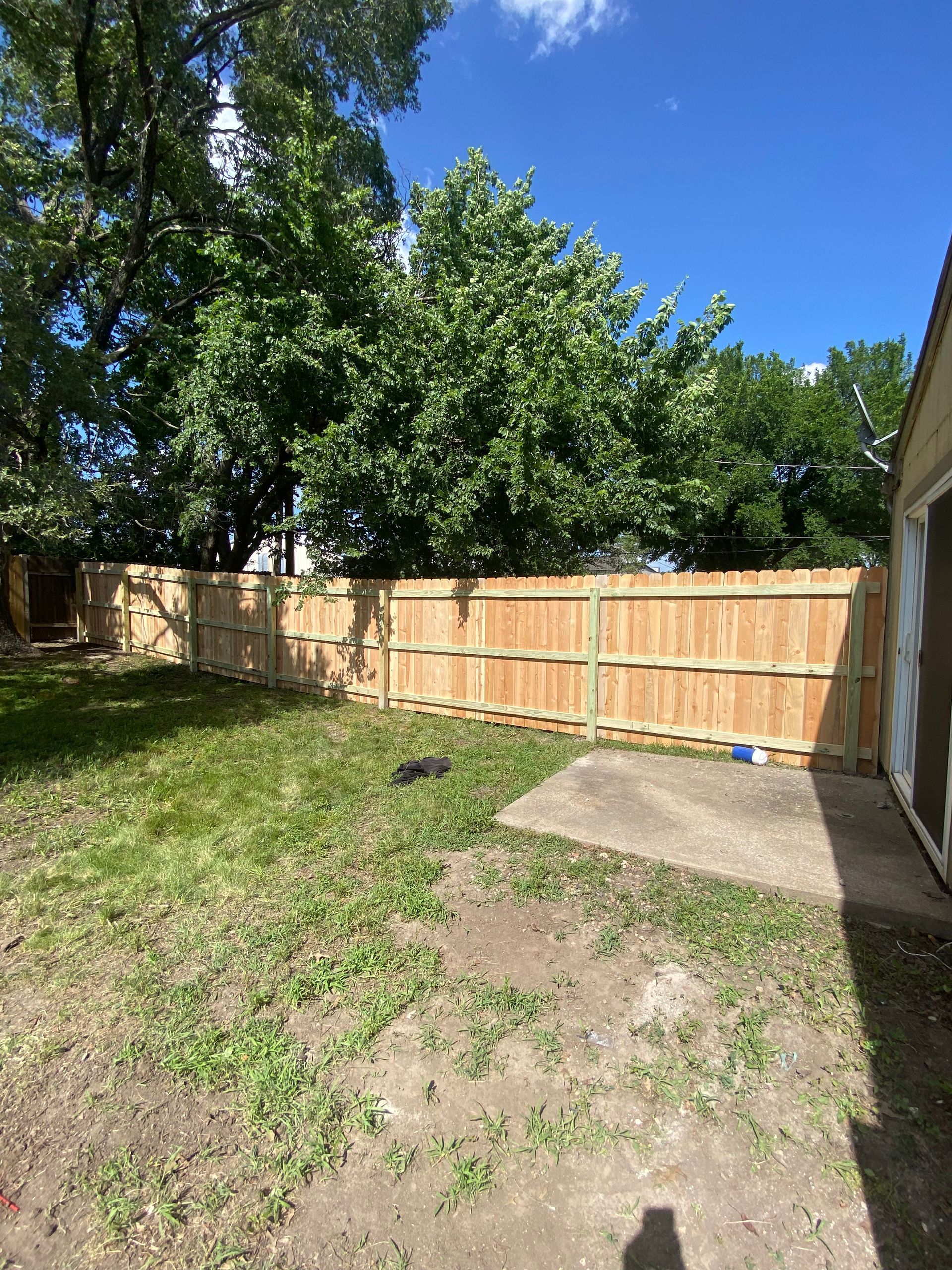A wooden fence is in the backyard of a house.