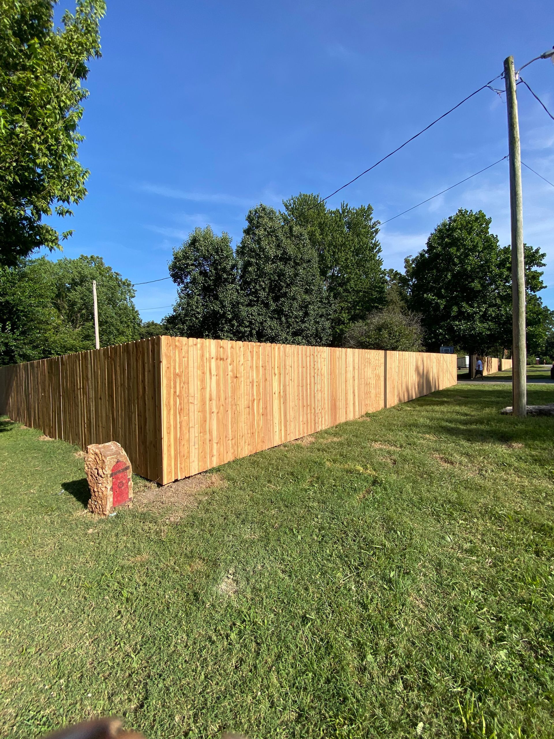 A wooden fence is sitting in the middle of a lush green field.
