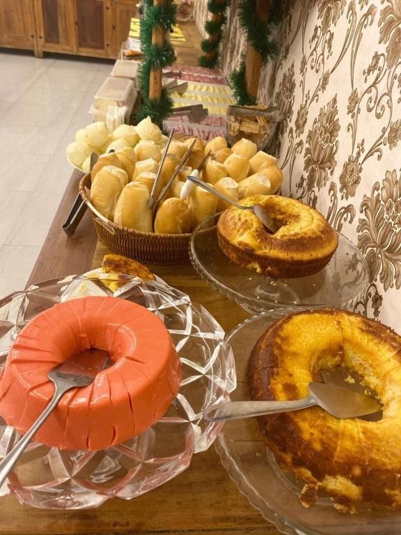 Uma mesa de bufê com pãezinhos, dois bolos e uma gelatina em formato de anel.