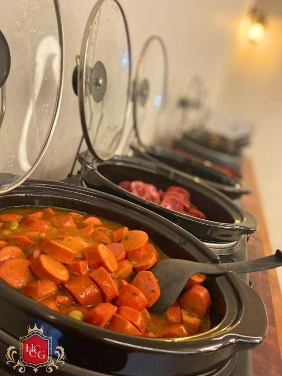 Buffet com panelas de cozimento lento, oferecendo ensopados e carnes, prontos para servir.