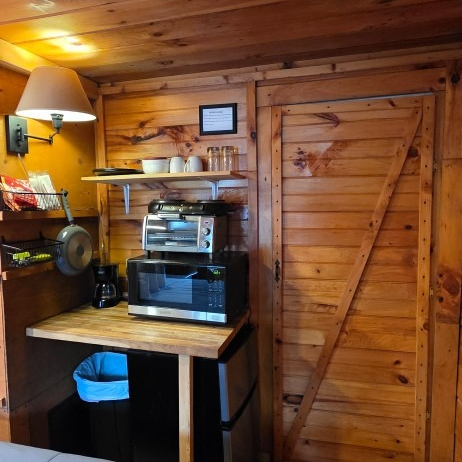Wood-paneled coffee nook with espresso machine, microwave, shelves, and lamp beside a closed wooden door