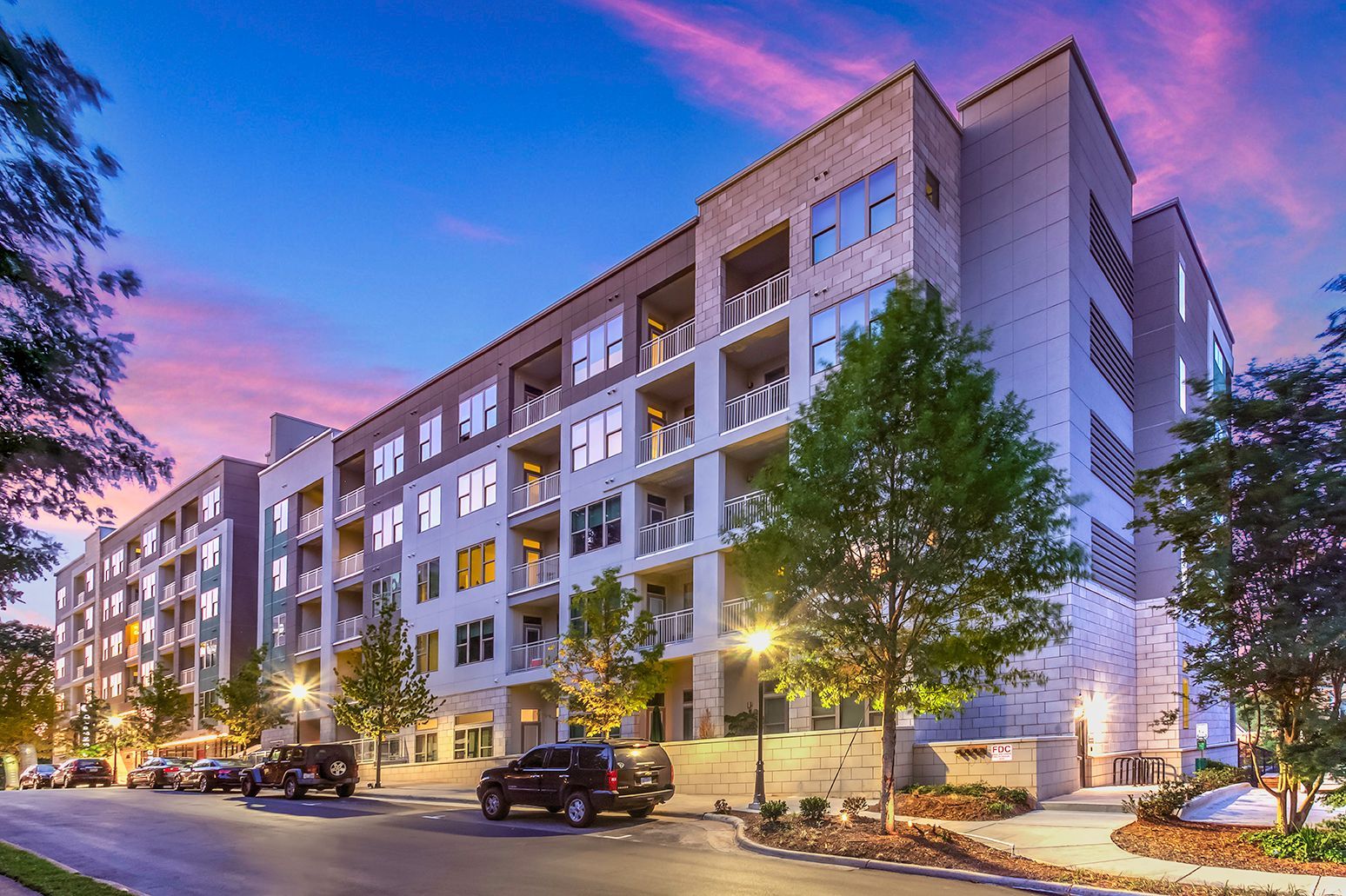 Exterior view of a modern apartment building with balconies at dusk.