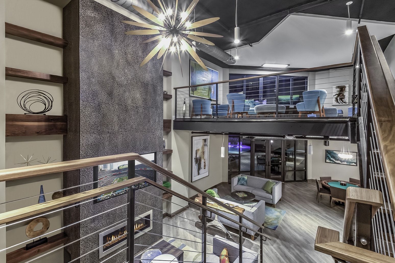 Modern multi-level home interior with open staircase, loft, fireplace, and chandelier.