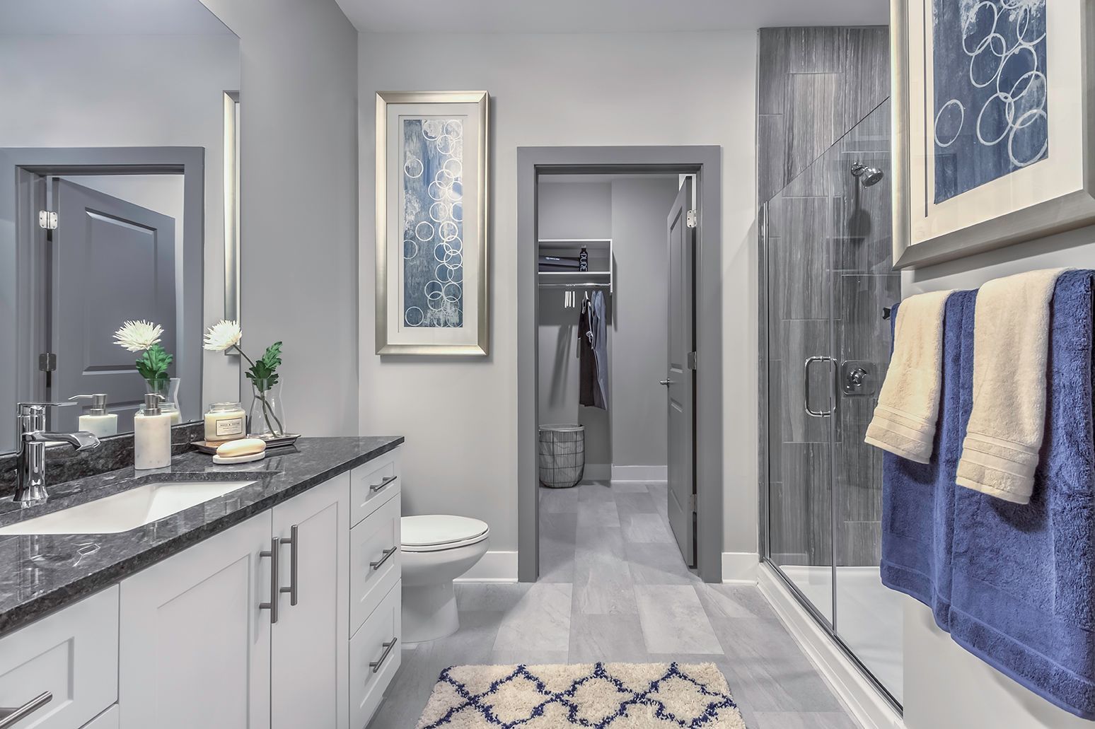 Modern bathroom with a double-sink vanity, glass-enclosed shower, and gray decor.