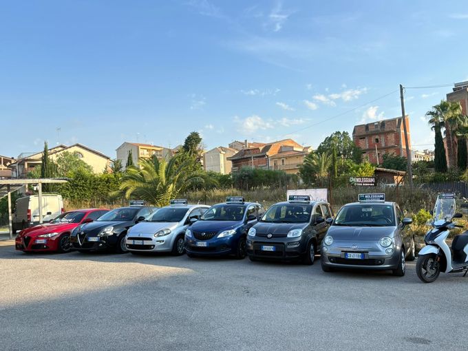 Uomo d'affari che utilizza un laptop e uno smartphone mentre è seduto sul sedile posteriore di un'auto.