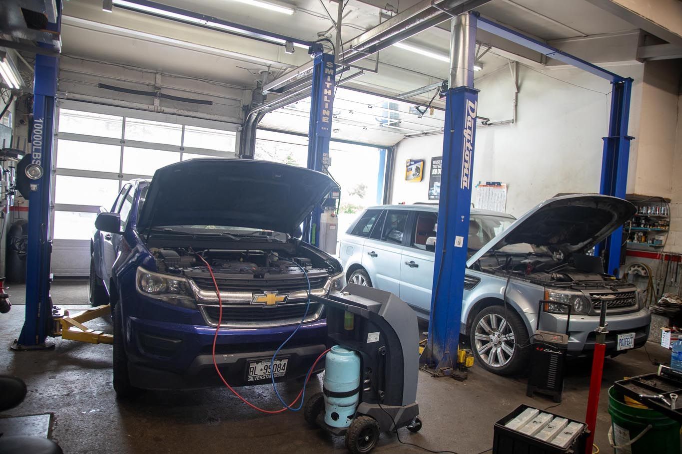 Auto repair shop with black car raised on a blue hydraulic lift and tools nearby