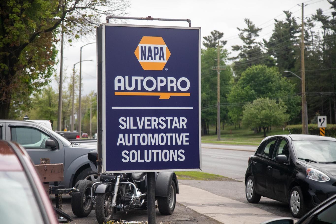 NAPA AutoPro sign for Silver Star Automotive Solutions beside parked cars on a rainy street