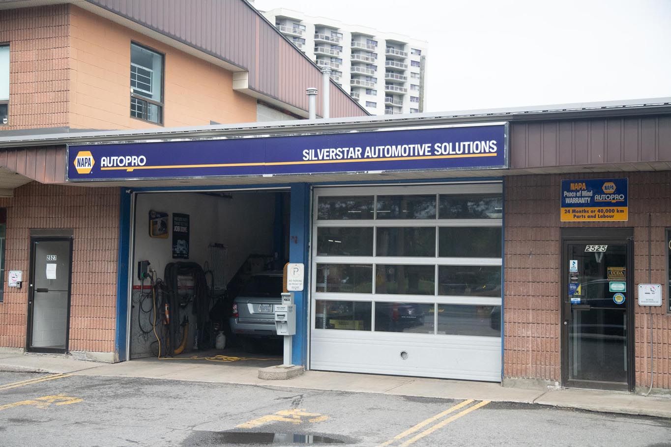 Auto repair shop exterior with open garage door and blue sign above the service bays