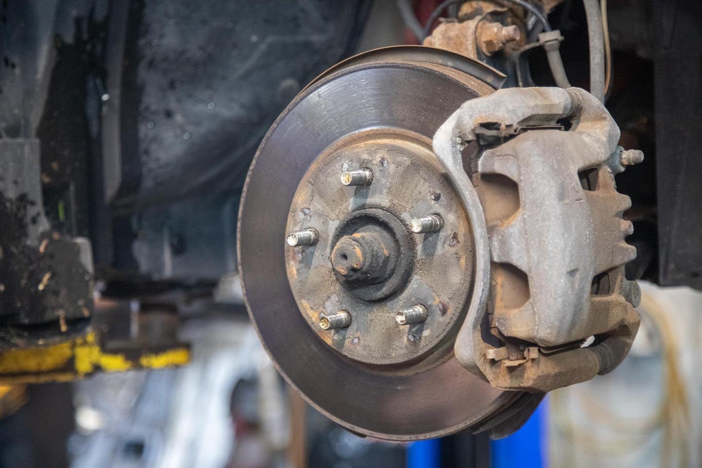 Close-up of a car brake disc and caliper in a garage on a lift