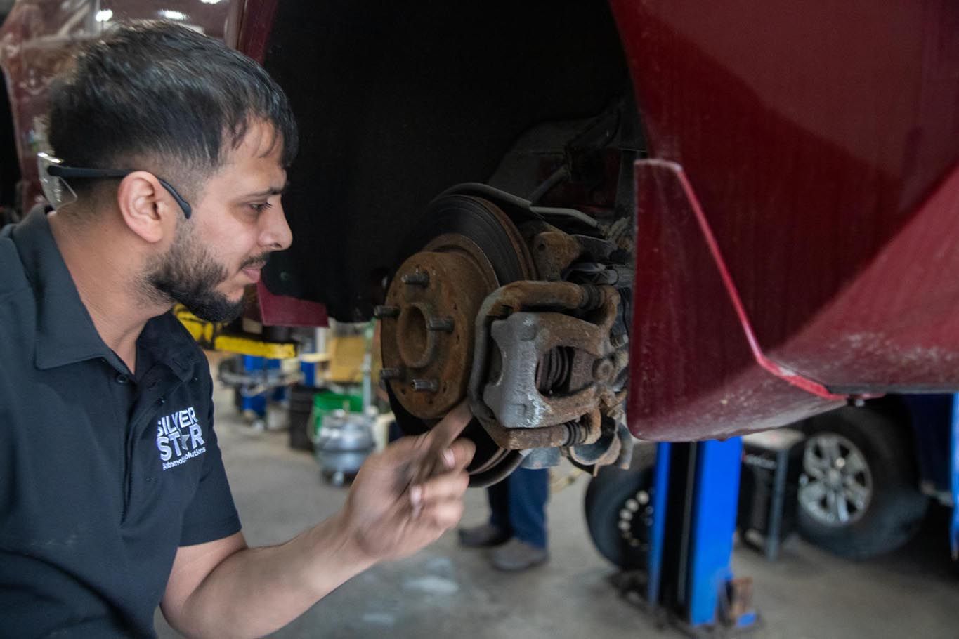 Mechanic inspecting a car’s exposed wheel brake assembly in a garage