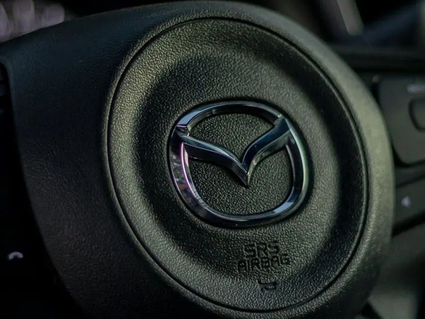 Close-up of a Mazda steering wheel logo on a black steering wheel center