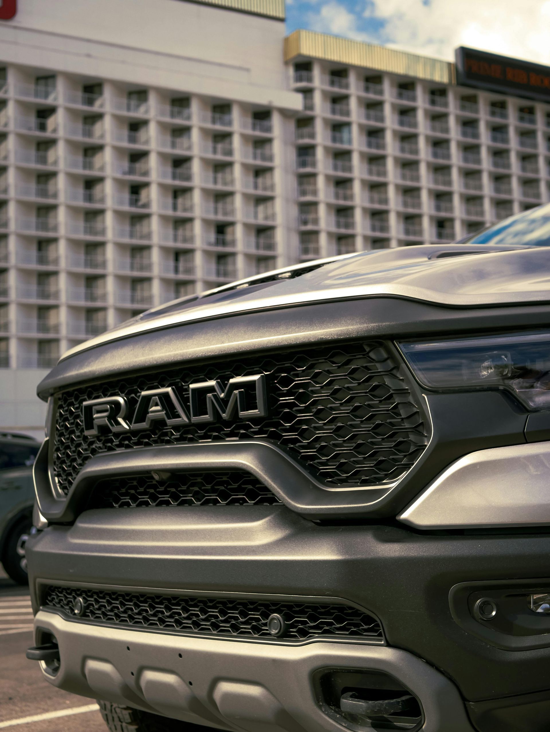 Front grille of a gray RAM truck parked in front of a modern building.