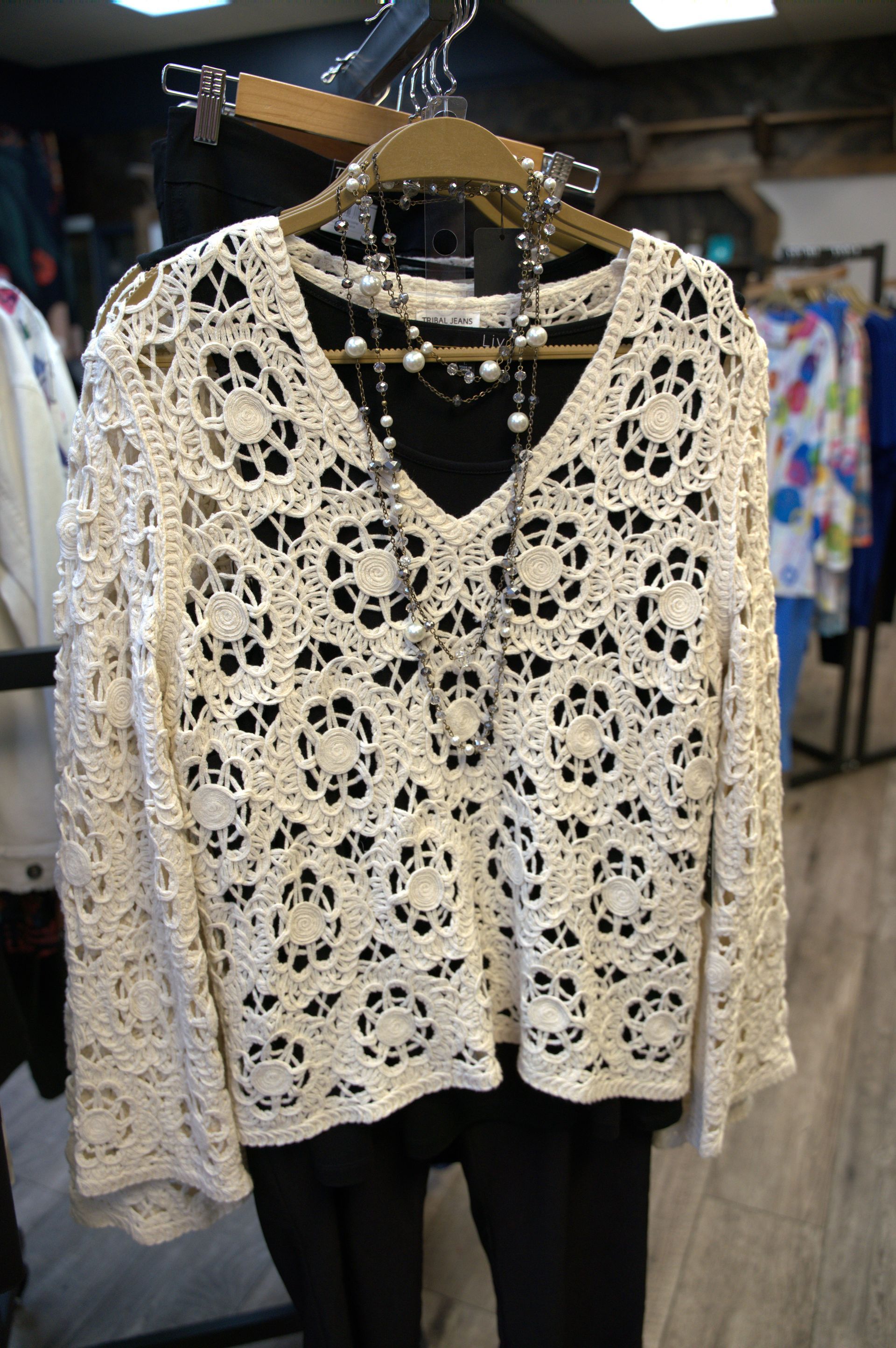 Cream-colored crochet top with a black undershirt and pants.