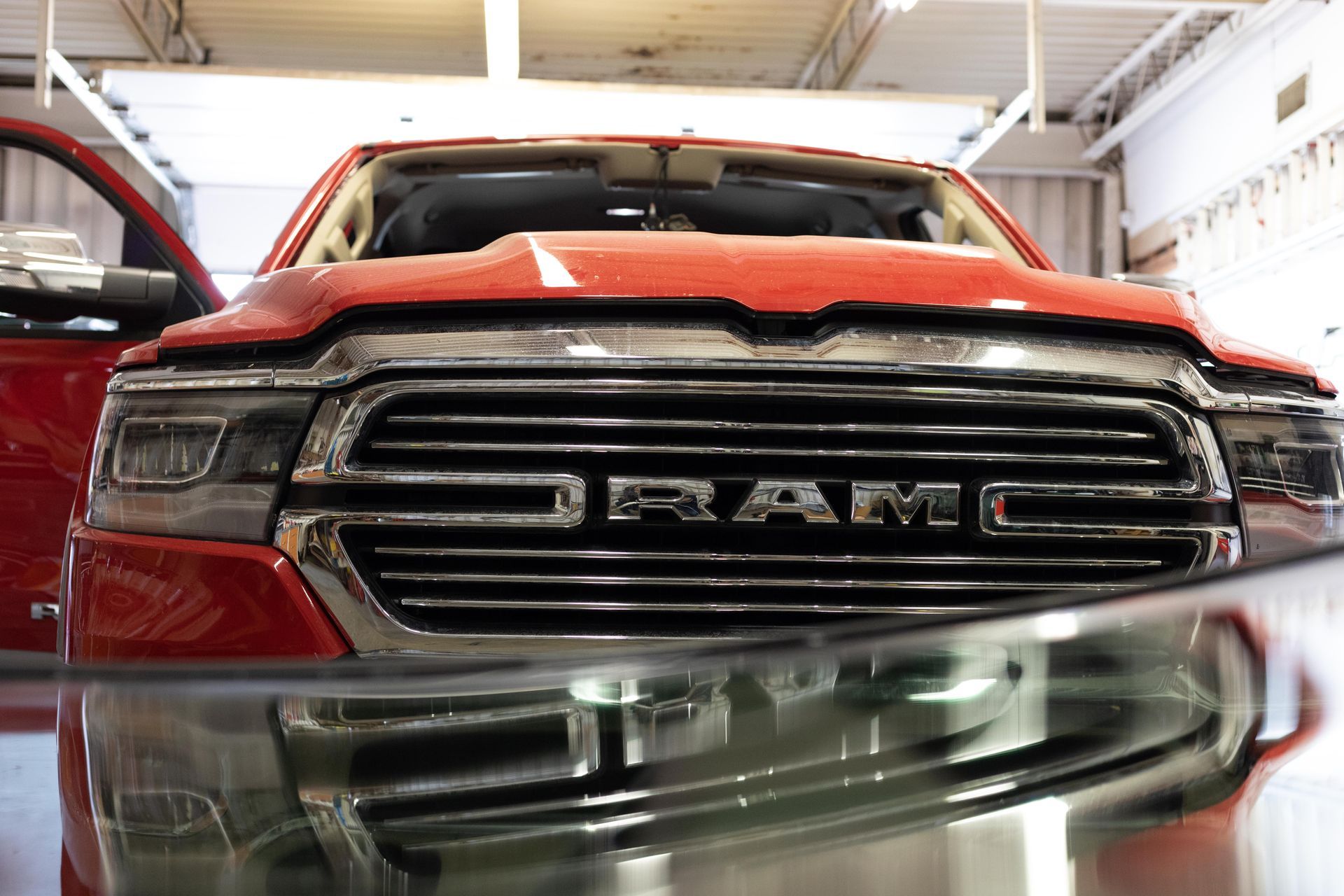 Red RAM truck in a garage, front grille close-up with motion blur in the foreground