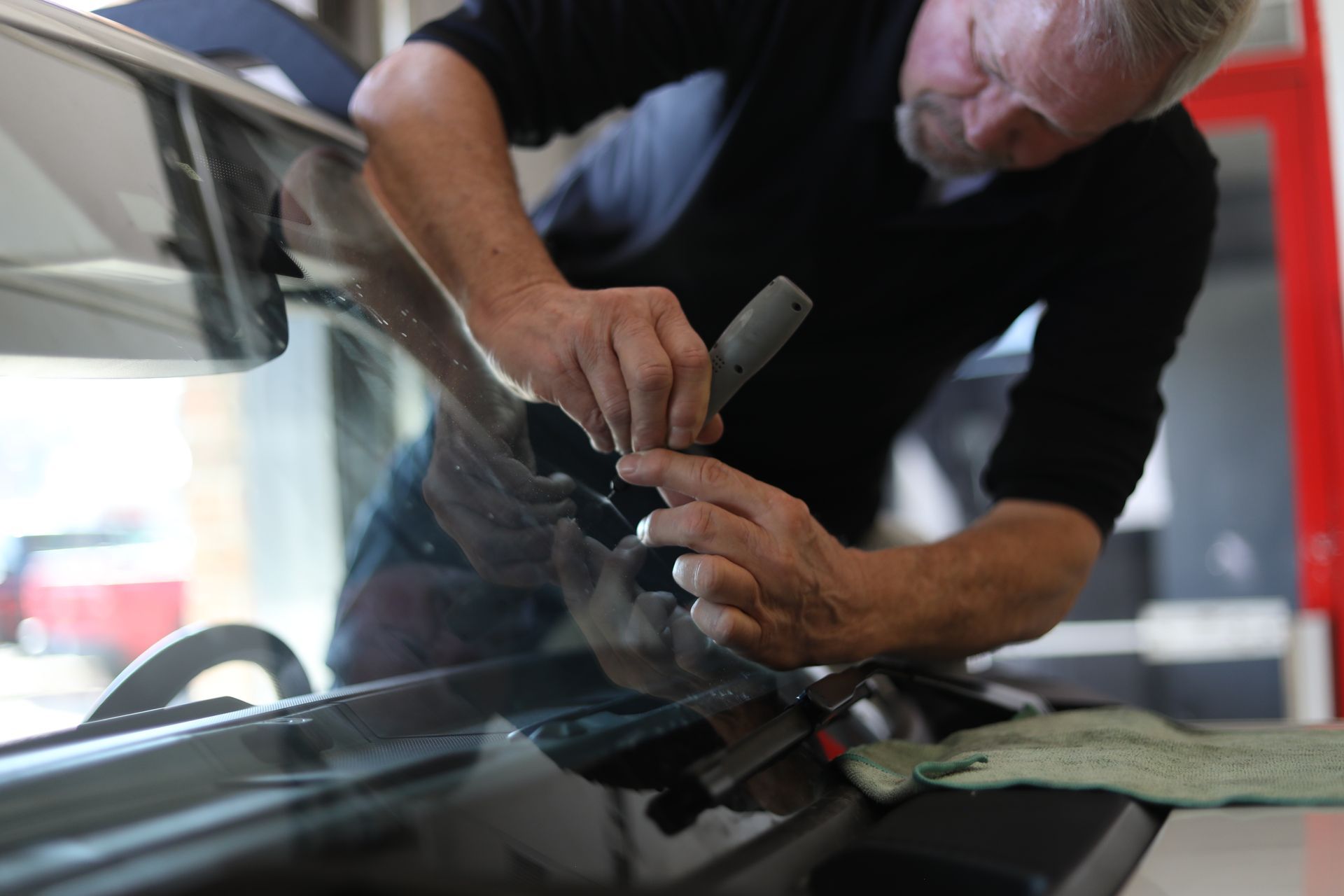 Technician installing a car windshield with a tool in a garage