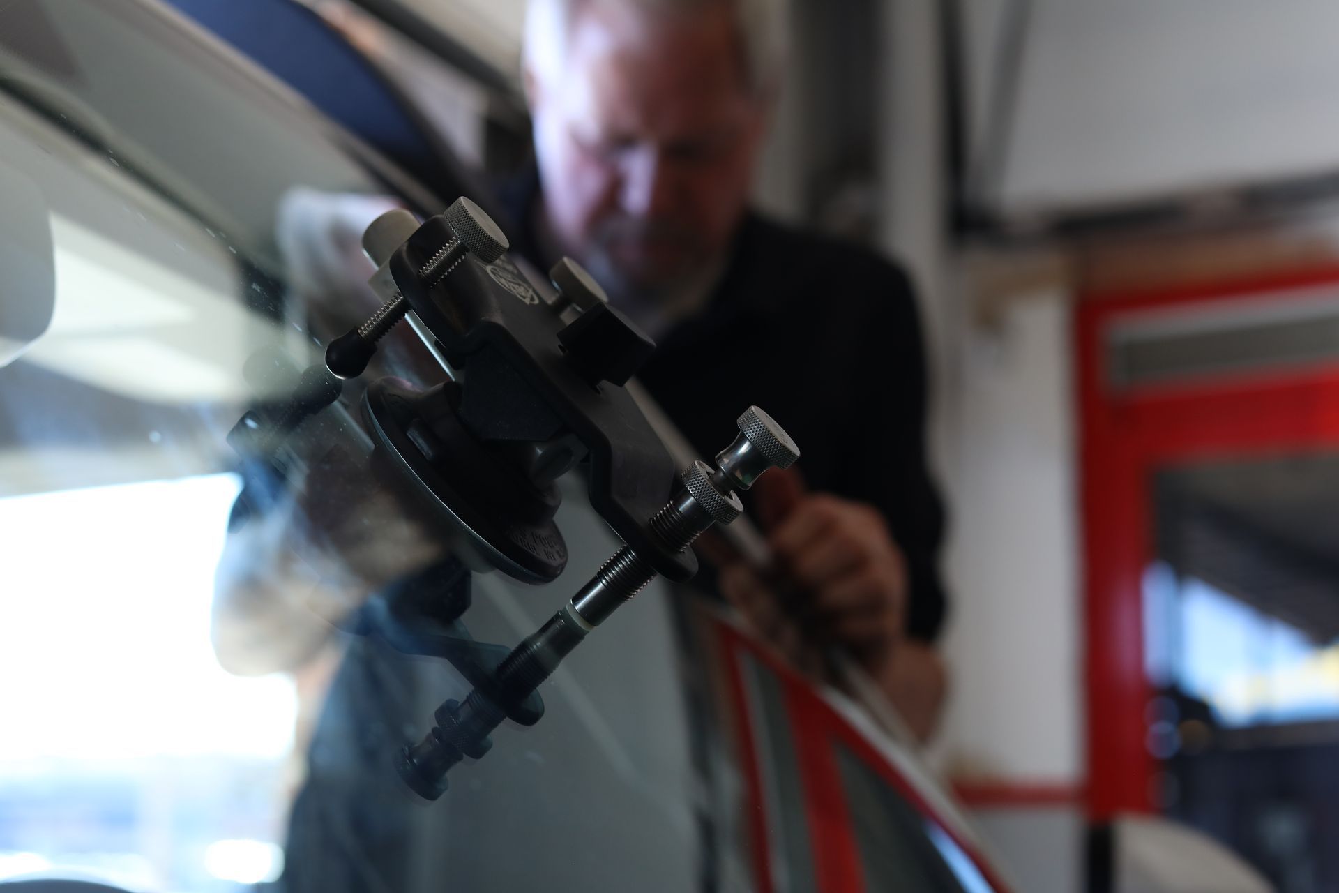 Close-up of a suction-cup camera mount on a car window, with a person blurred in the background