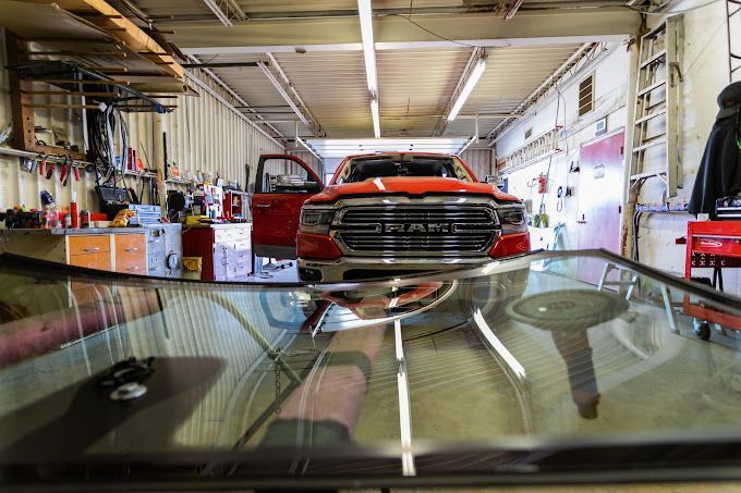 RAM windshield replacement in Amarillo, TX Red truck in a garage, seen through a car windshield with wipers in the foreground