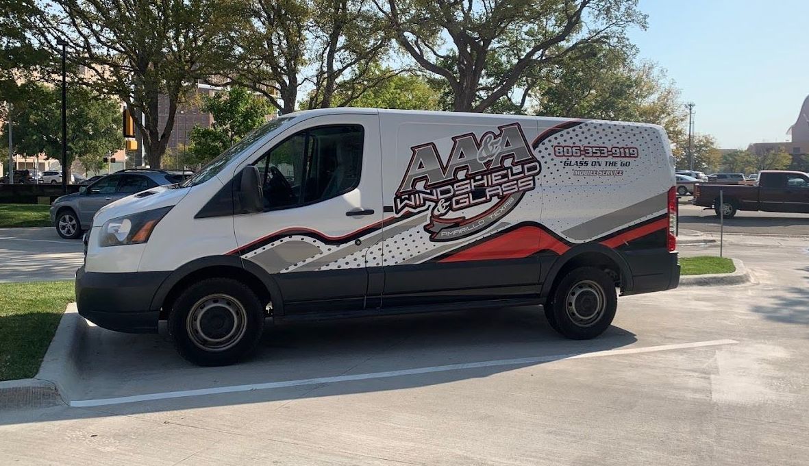 White and black service van with red graphics parked in a lot on a sunny day