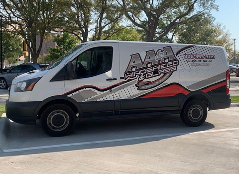 White delivery van with red and black graphics parked on a street under trees