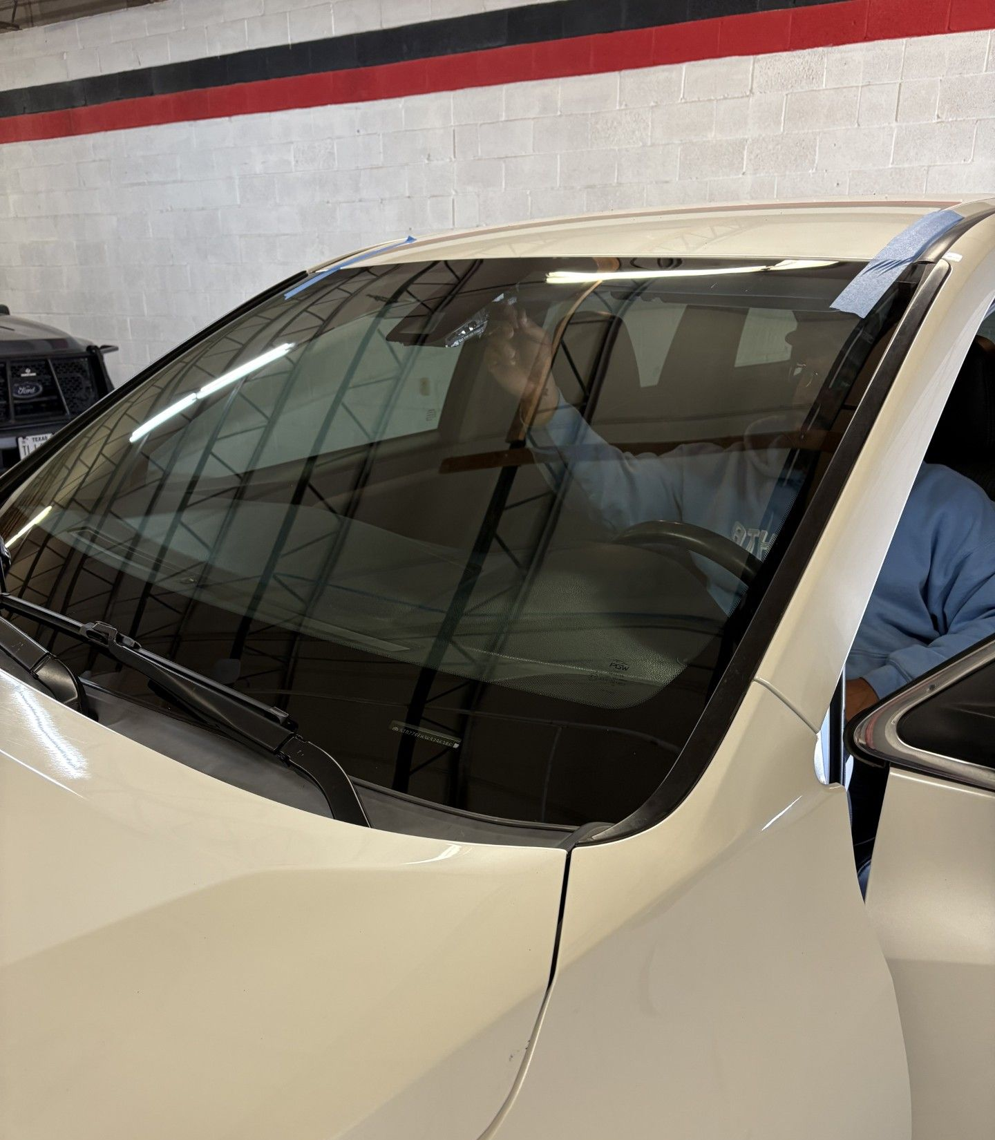 White SUV parked in a garage, viewed through the front windshield with reflections visible