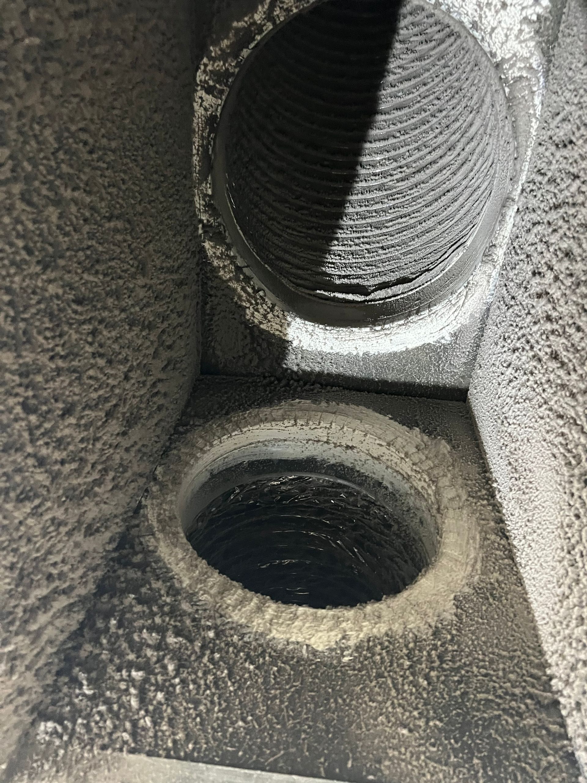 Close-up of a gray carpeted speaker enclosure with circular speaker openings and dust buildup