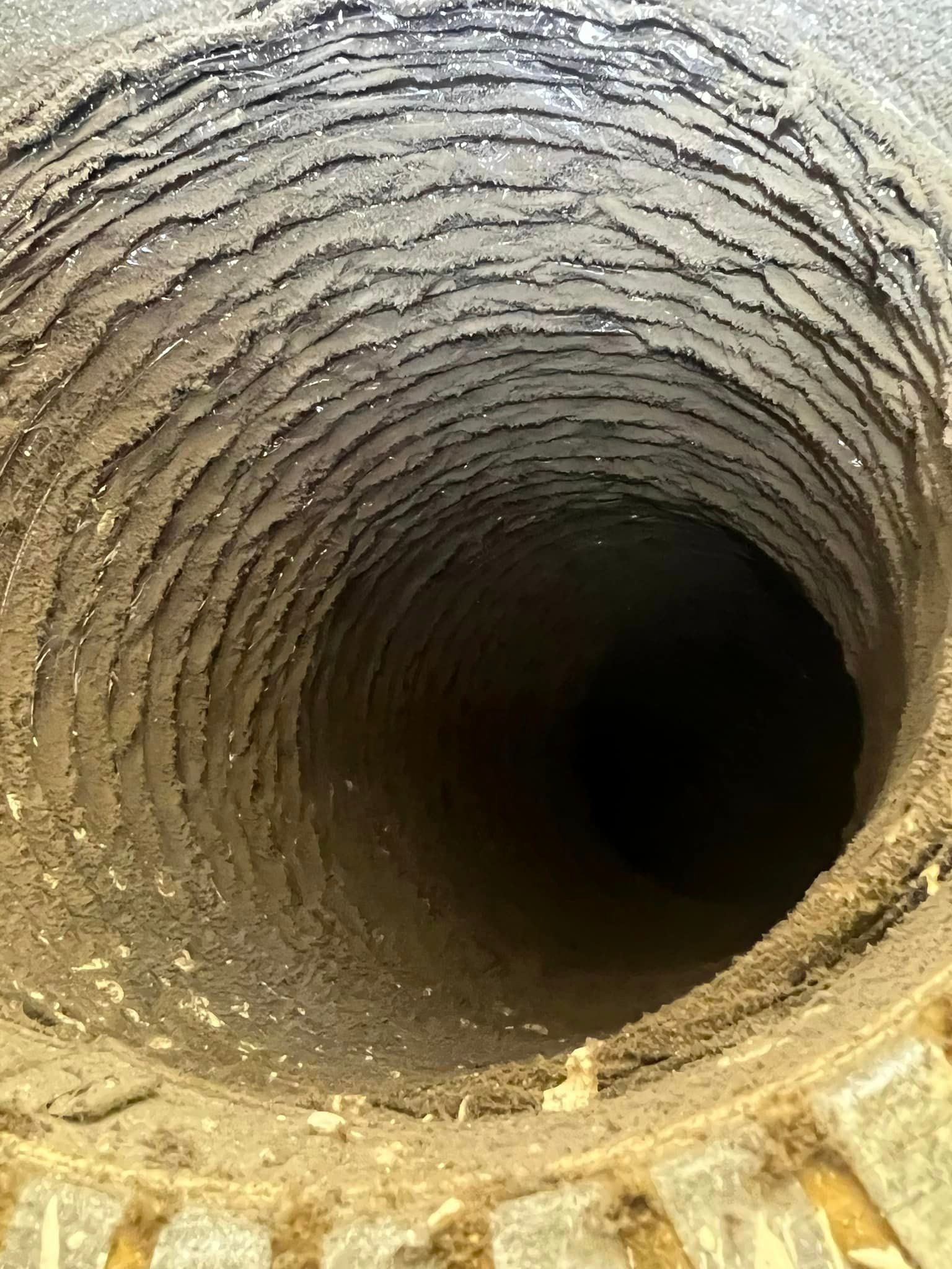 Interior of a deep cylindrical stone well with rough, textured walls and a dark opening below