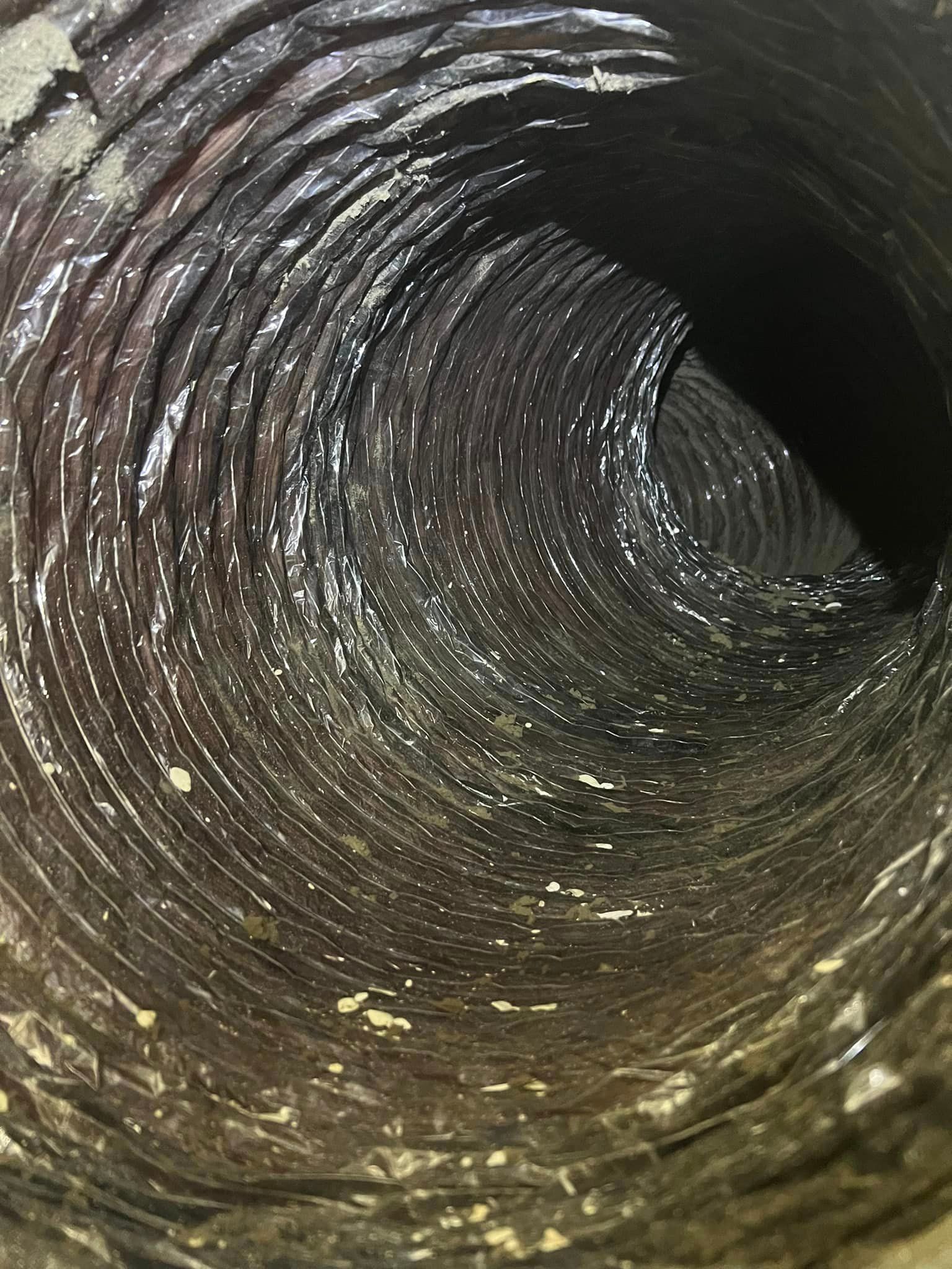 Inside a dark, muddy drainpipe with a spiral of grime and debris along the walls