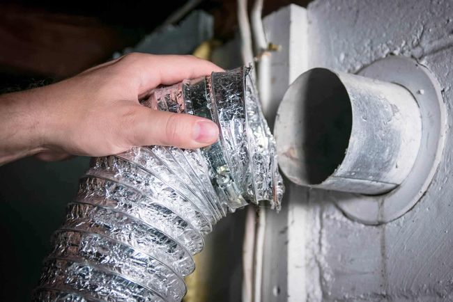 Hand connecting a silver flexible duct to a round metal vent opening
