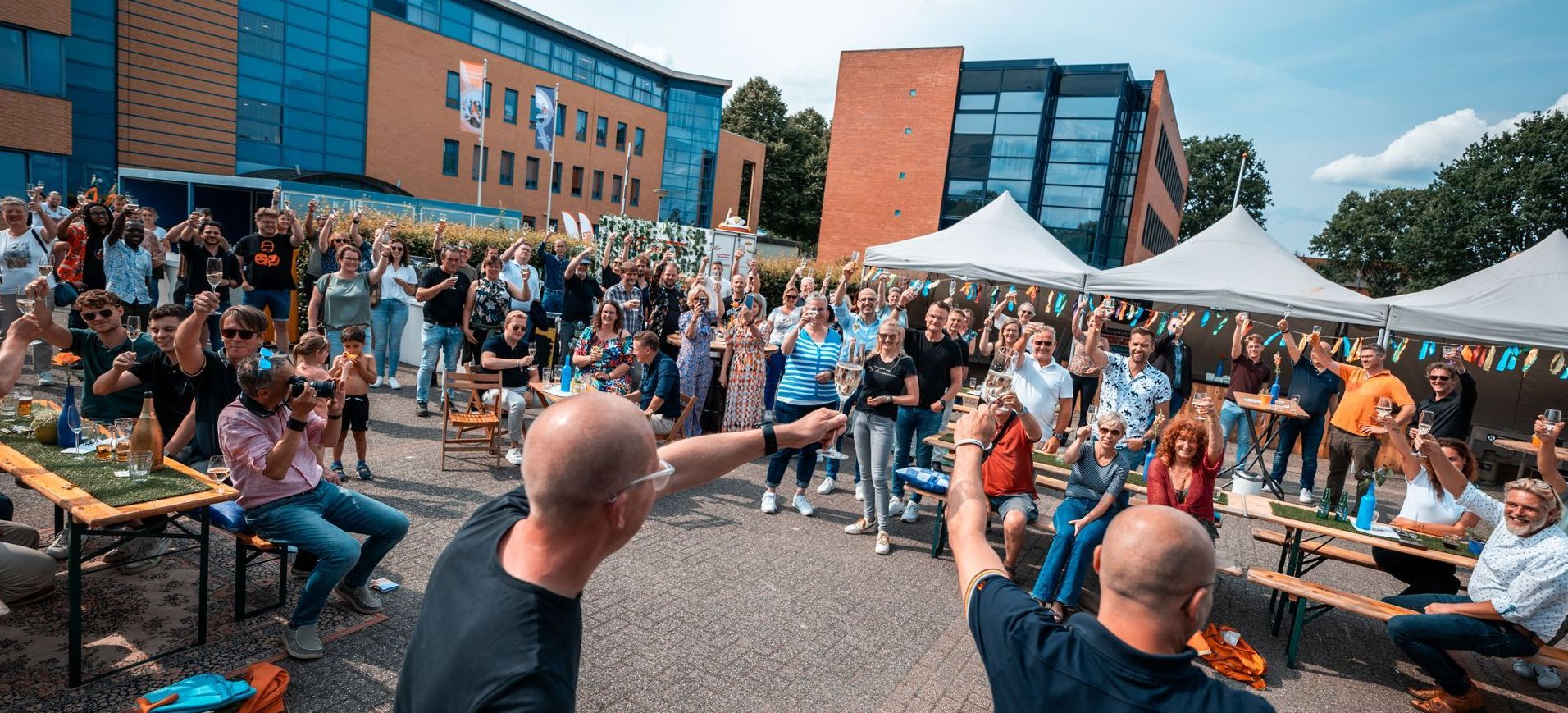 Afbeelding met daarop 2 communityleden van Growing Emmen die gezamenlijk naar een foto met daarop andere leden van Growing Emmen kijken.