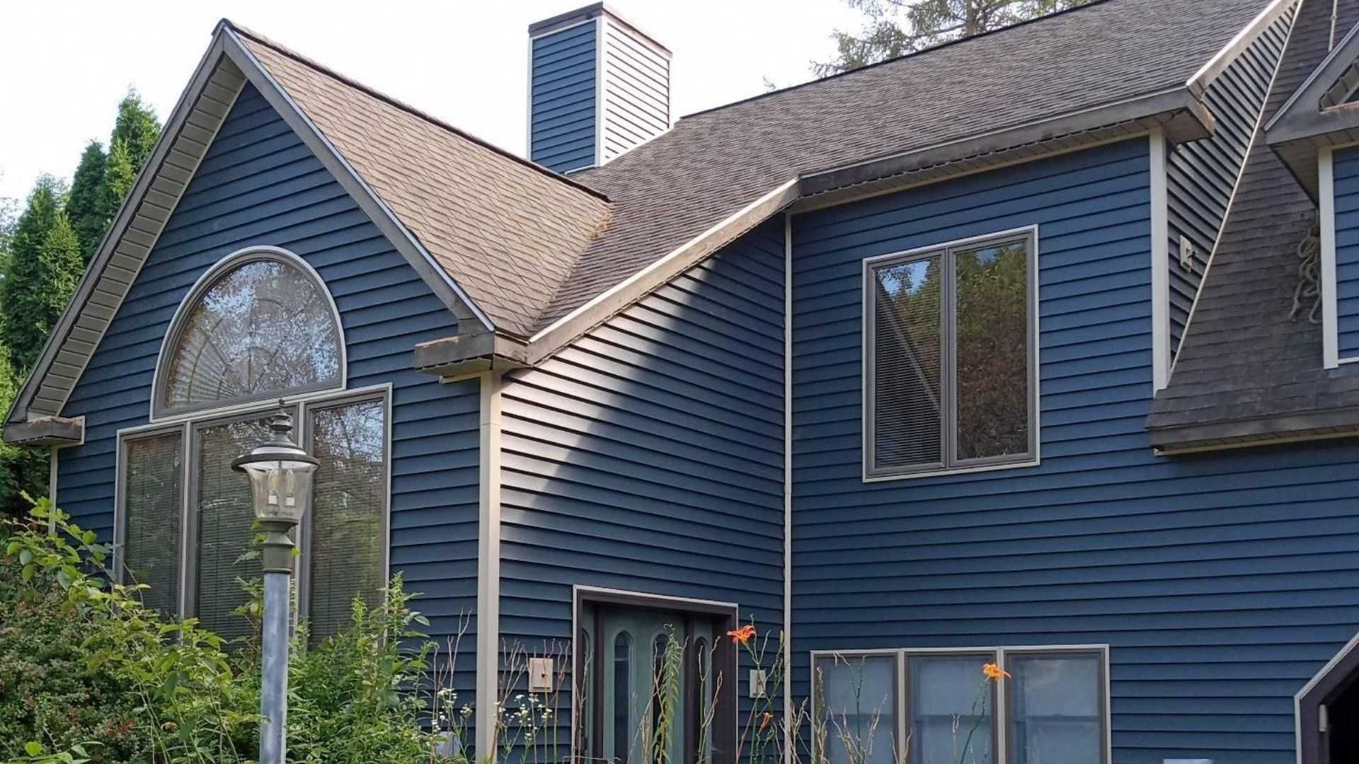 Blue house with a dark roof and large windows.