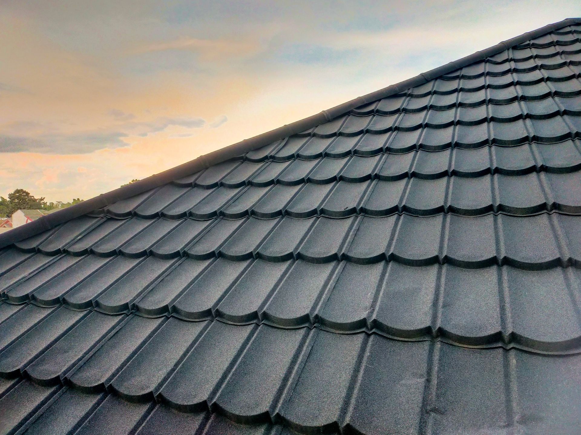 Gray tiled roof at sunset with a cloudy sky in the background