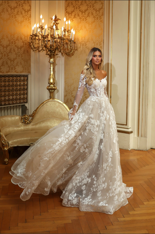 Woman in an off-the-shoulder, floral wedding dress, posing indoors.
