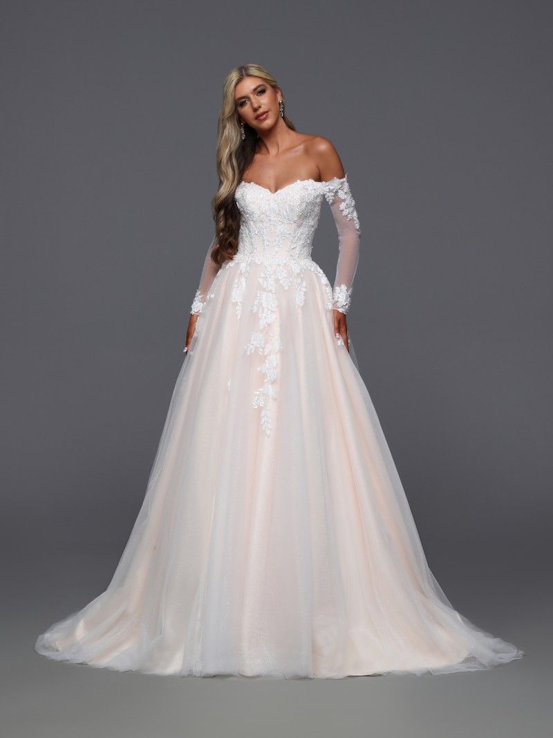 Woman wearing a white, off-the-shoulder wedding gown with long sleeves and a full skirt.