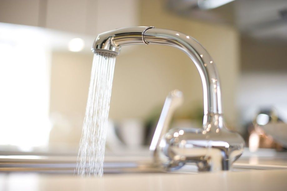 Water is running from a faucet in a kitchen sink.