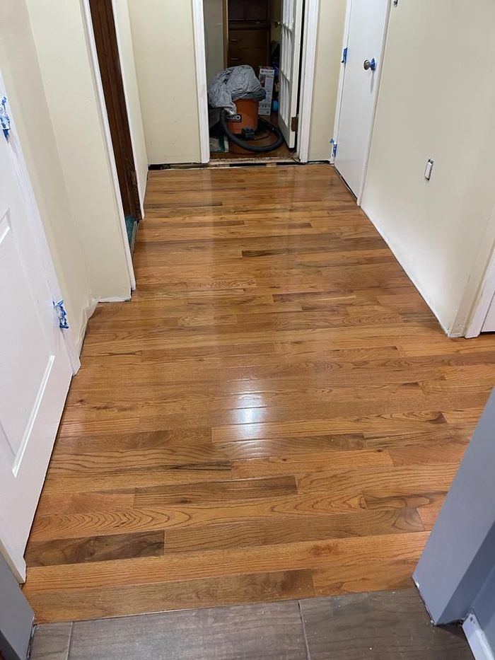 Hallway with newly installed and stained hardwood floors. Doors line the walls.