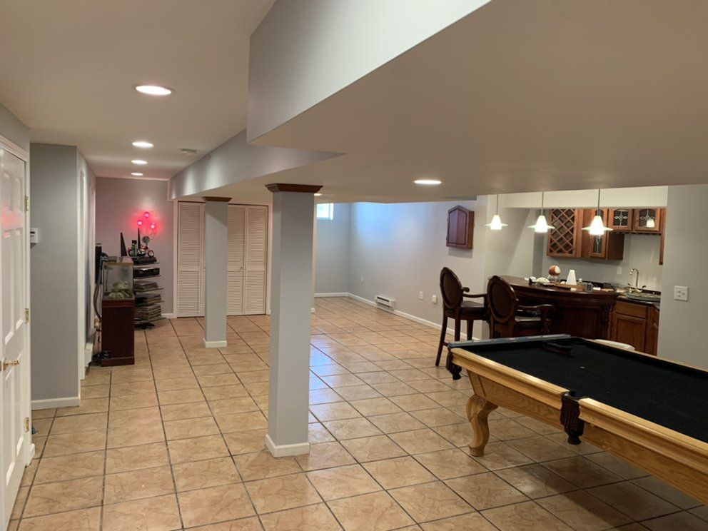Basement with pool table, bar, and columns. Beige tile floor, gray walls, and recessed lighting.