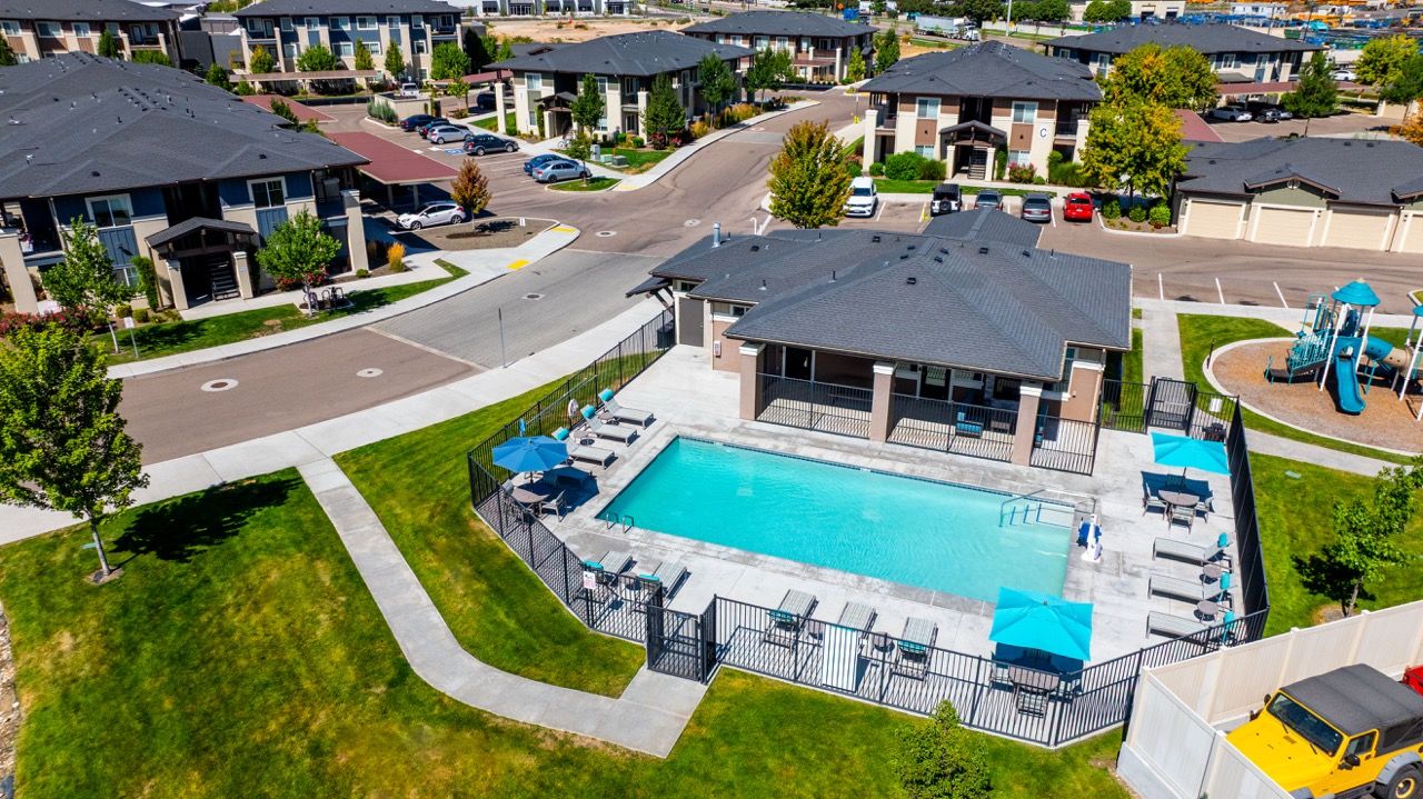 Aerial view of a fenced community pool with lounge chairs and a clubhouse.